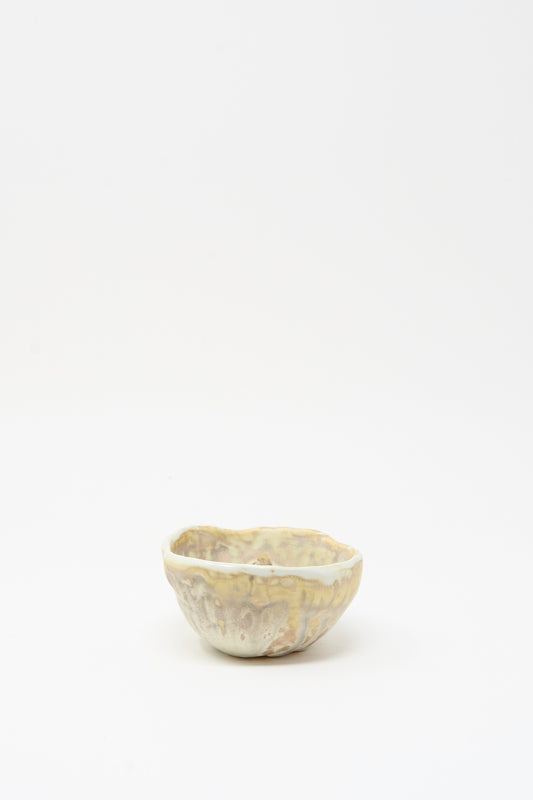 The MONDAYS Soda-Fired Pinched Bowl I, a small handmade bowl with an irregular pinched rim and a mottled light beige glaze, is displayed on a plain white background.
