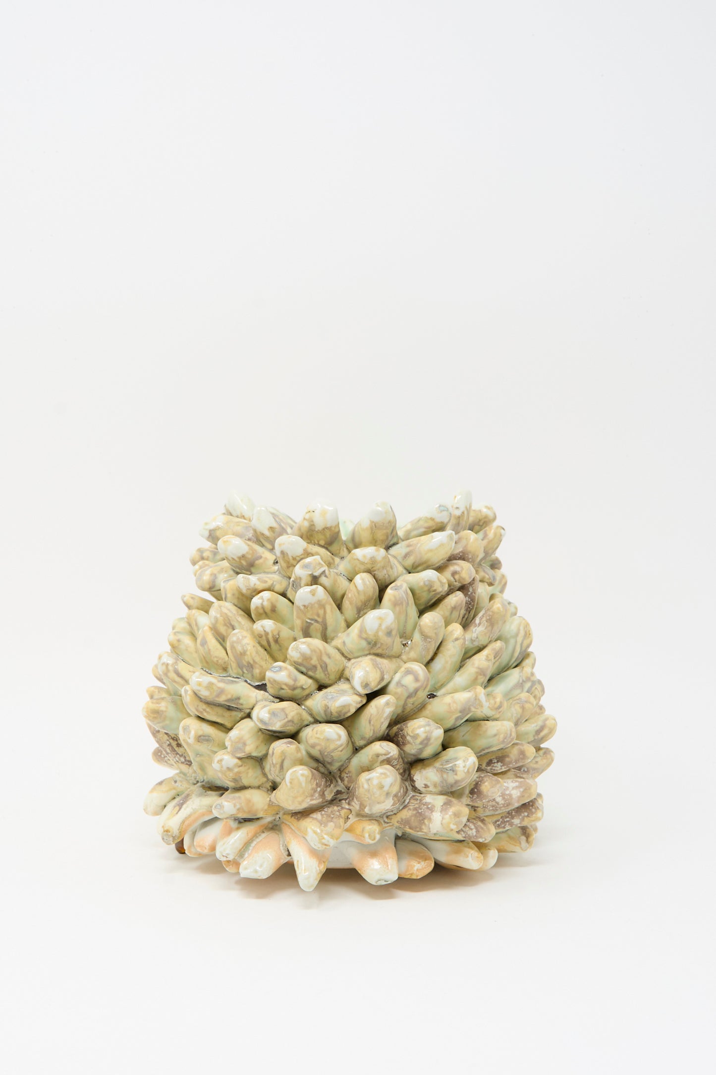 The MONDAYS Soda-Fired Rasmus Bump Vase features small, round, beige and greenish pine cone-like scales and is handmade from porcelain, shown here against a plain white background.