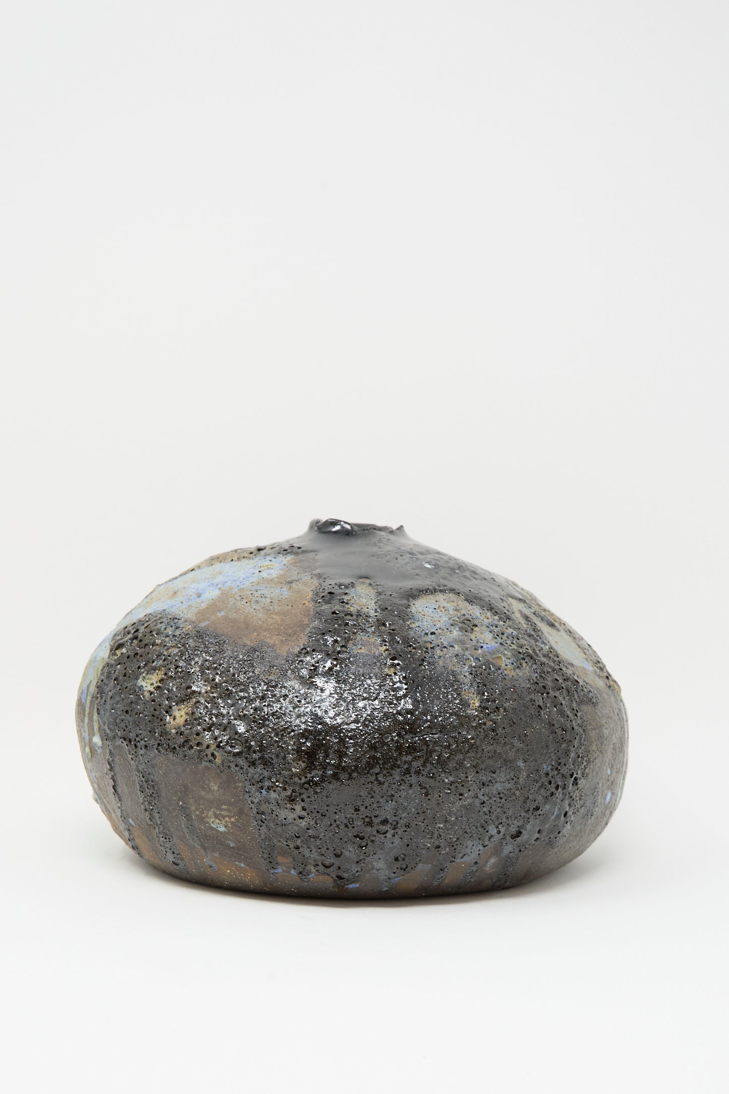 The MONDAYS Textured Moon Vase in Black features a handmade, round design with a glossy, uneven surface accented by subtle blue and brown patches, shown against a white background.