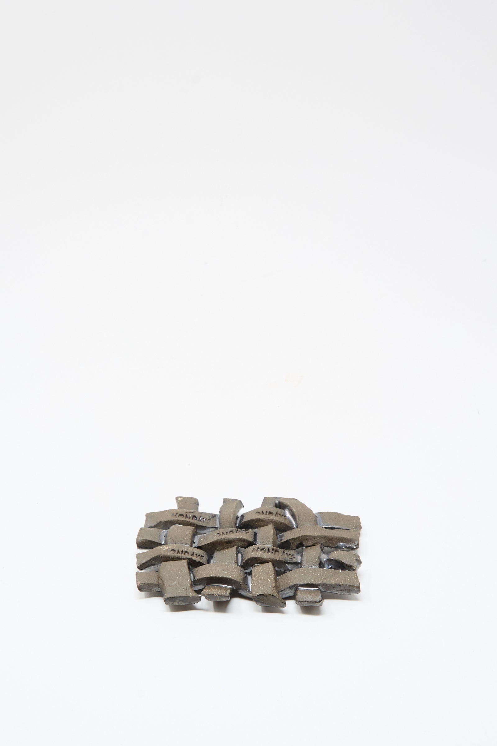 The MONDAYS Woven Dish in Charcoal is a small, rectangular ceramic piece with interwoven curves and a subtle charcoal glaze, displayed on a plain white background.
