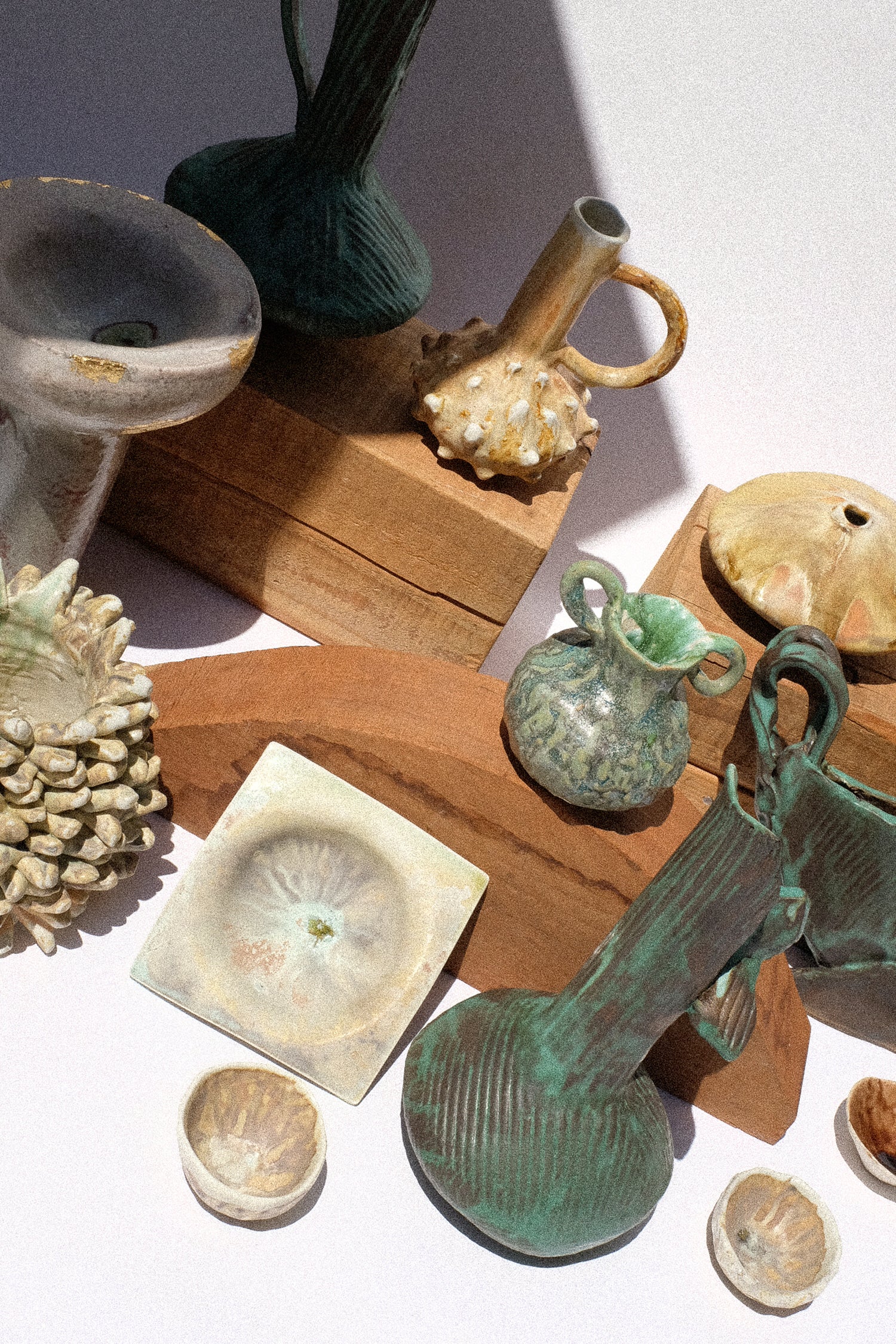 Collection of ceramic and stone artifacts on a wooden surface with a white background