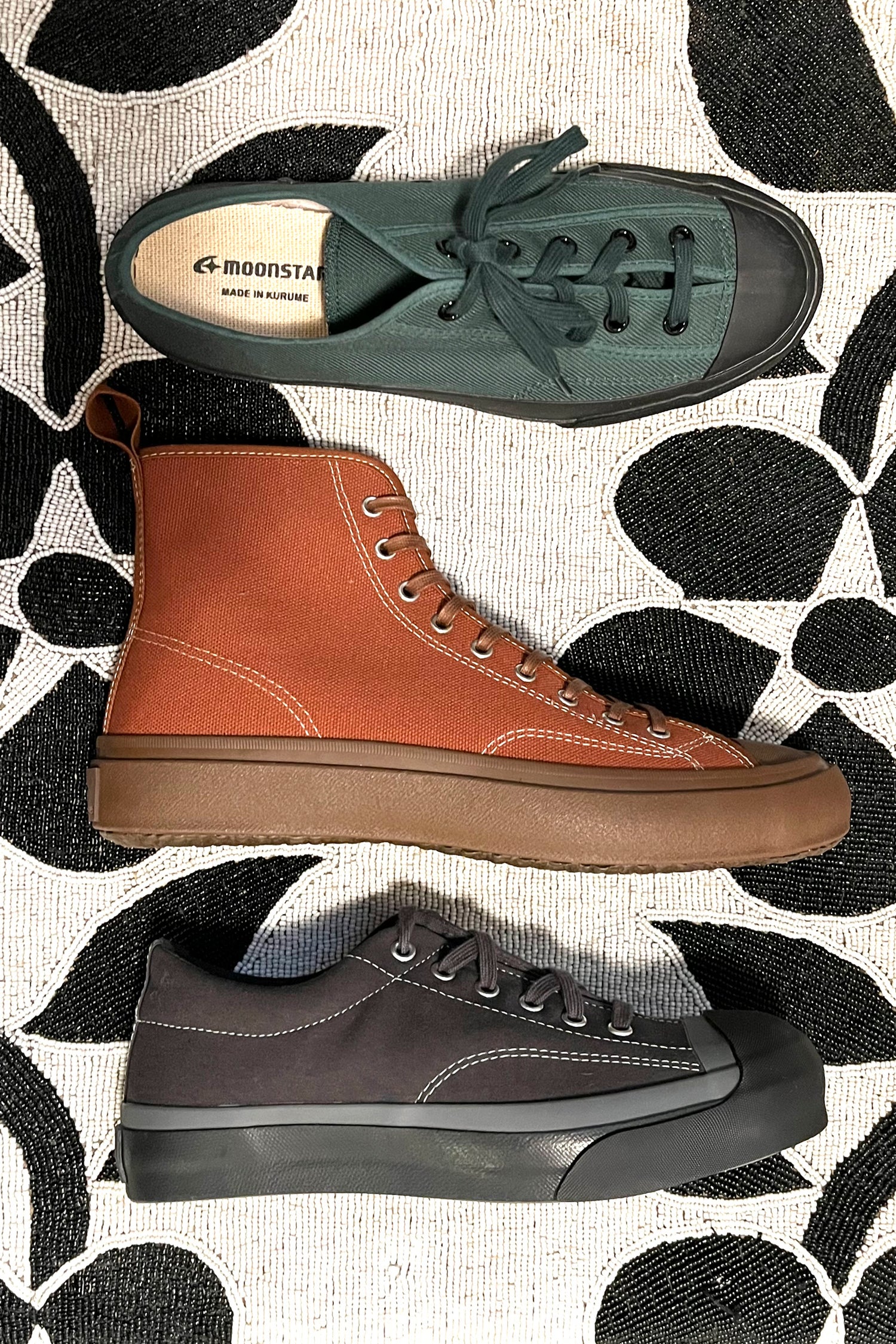 An image of the Gym Classic Sneaker in Dark Green, Hi Basket Sneaker in Brown, and Gym Court Sneaker in Charcoal from Moonstar on a beaded chair.