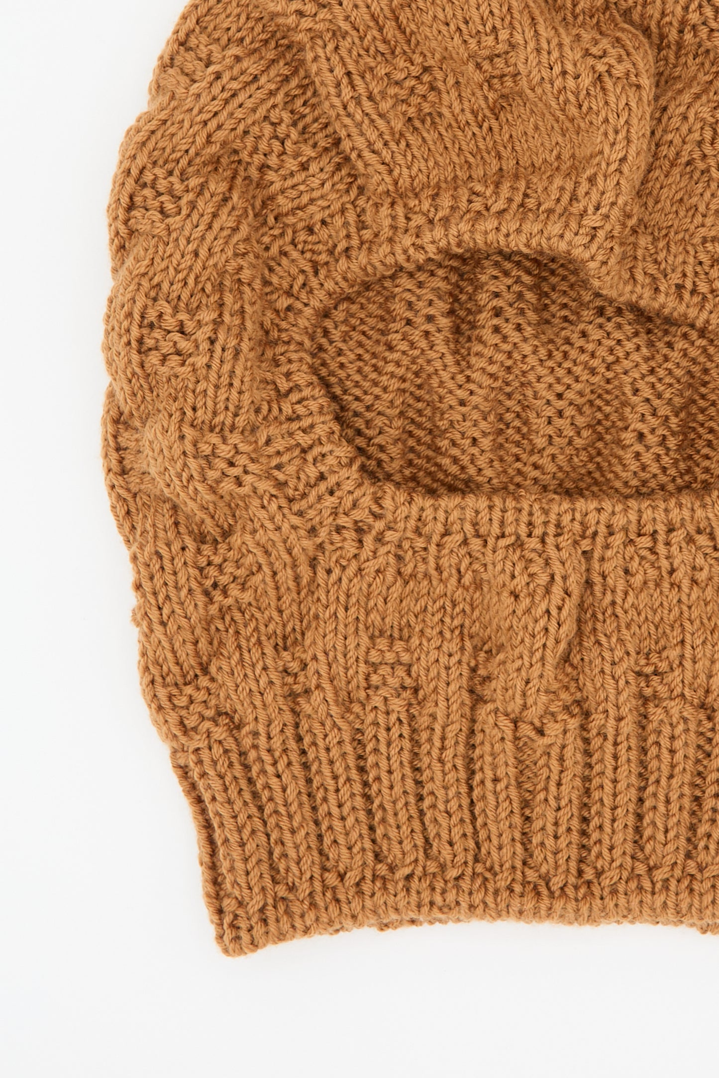 Close-up image of the Maria La Rosa Balaclava in Rust, hand-knit from wool and featuring a single large eye opening.