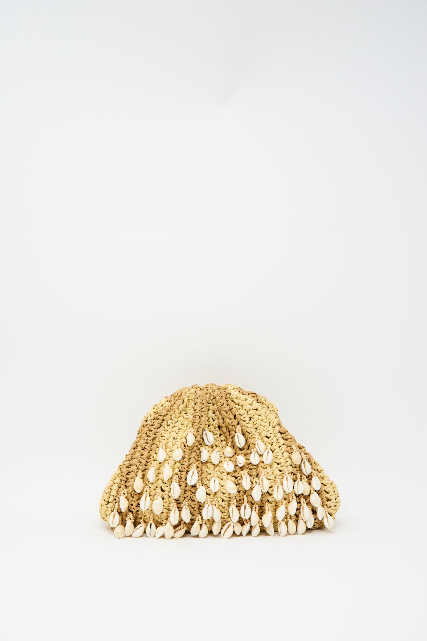 The Shell Mini Game Bag in Natural by Maria La Rosa, a woven mini clutch with shell embellishments, rests on a plain white background. It features a discreet interior pocket and an optional chain shoulder strap.