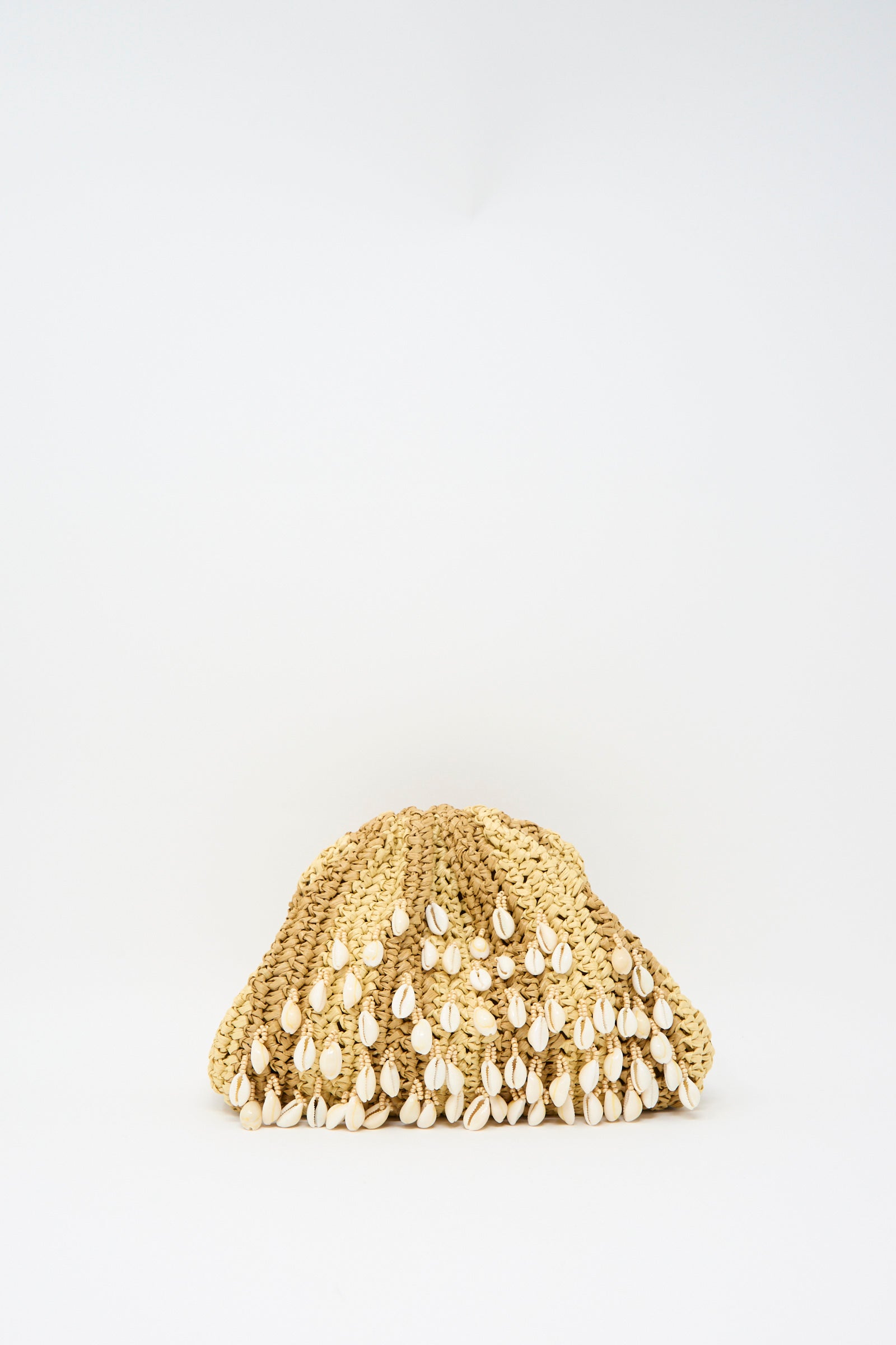 The Shell Mini Game Bag in Natural by Maria La Rosa, a woven mini clutch with shell embellishments, rests on a plain white background. It features a discreet interior pocket and an optional chain shoulder strap.