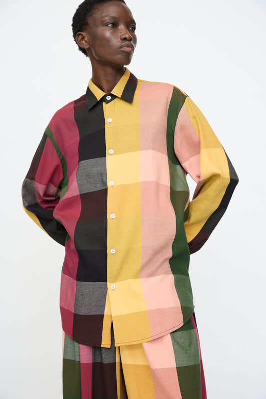 A person wears the Marrakshi Life Button Down Shirt in Plaid Multi, featuring a relaxed fit and large multicolored checks, paired with matching pants against a plain background.
