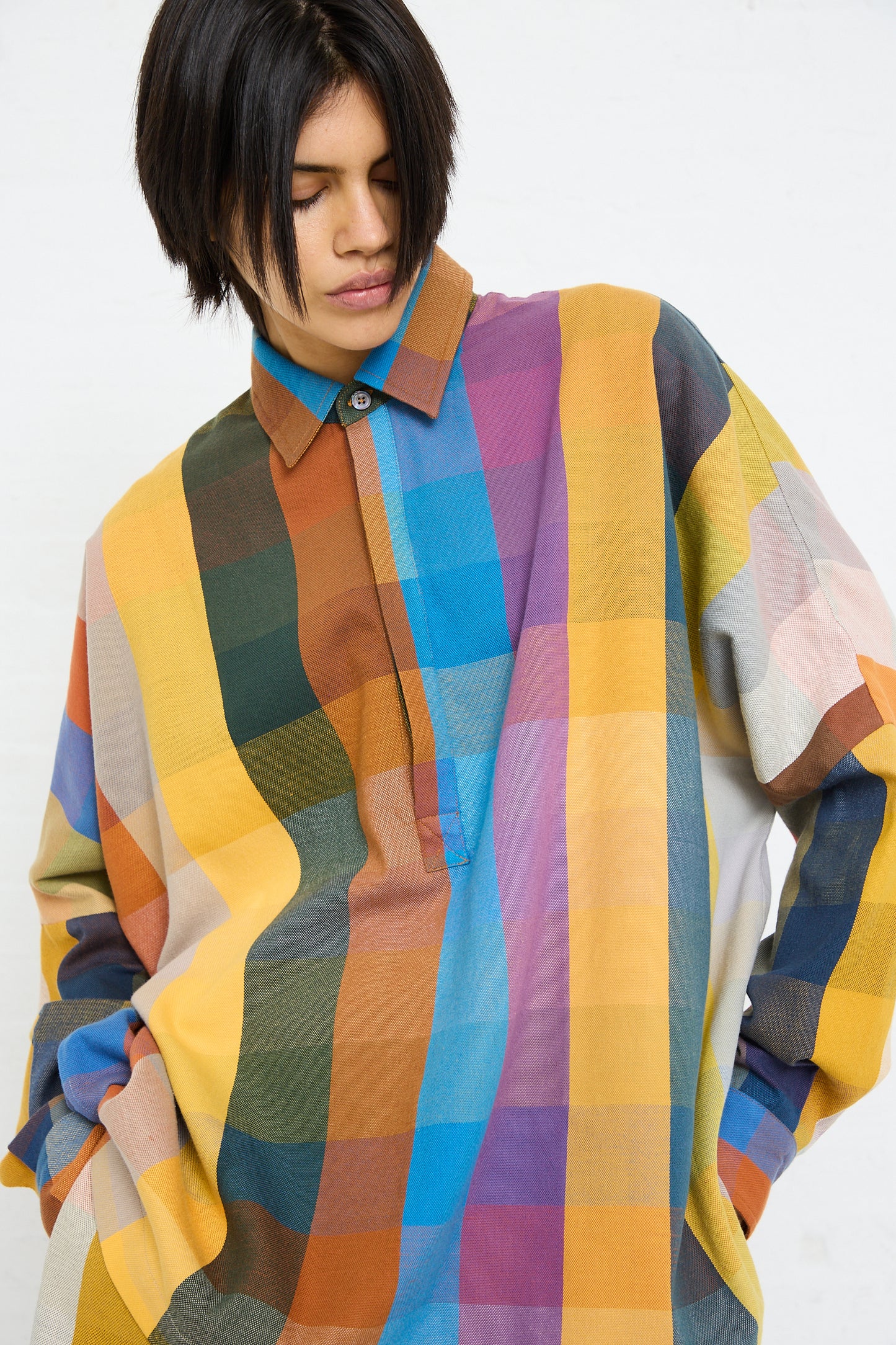 A person in a multicolored Marrakshi Life Cropped Tunic in Multi Check with eyes closed.