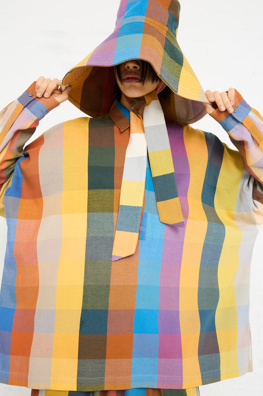 A person wearing a colorful Marrakshi Life Hat in Multi Check with an oversized hood covering their face, standing against a plain background.