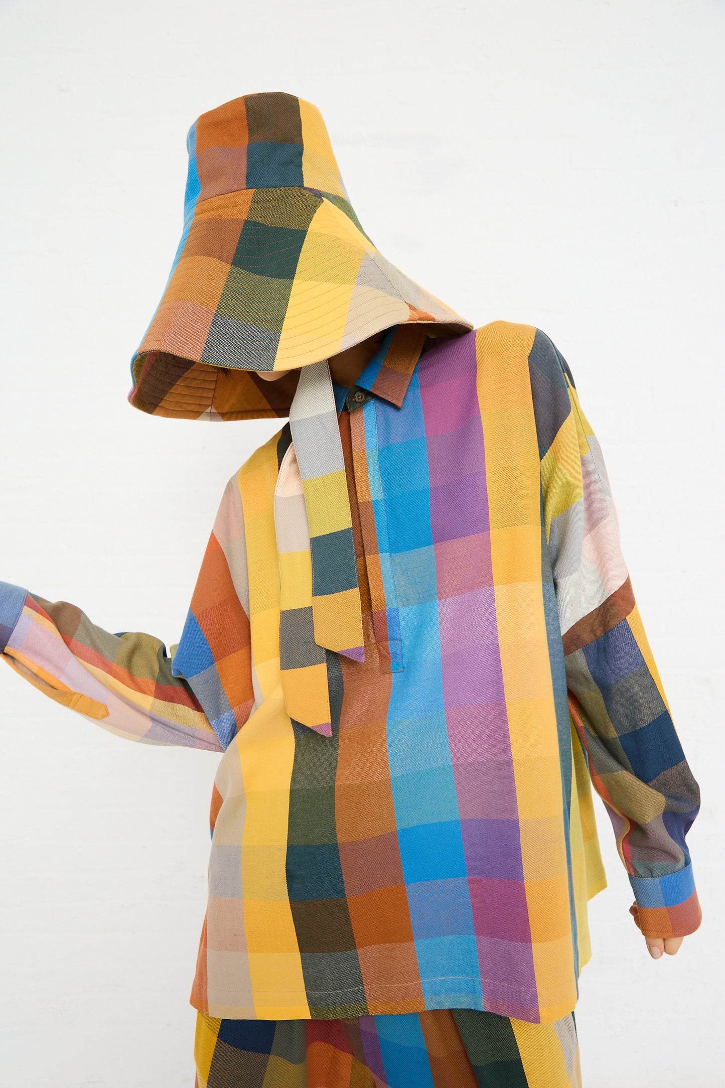 Person wearing a colorful Marrakshi Life Hat in Multi Check patchwork hoodie with the hood up, obscuring their face, posed against a white background.