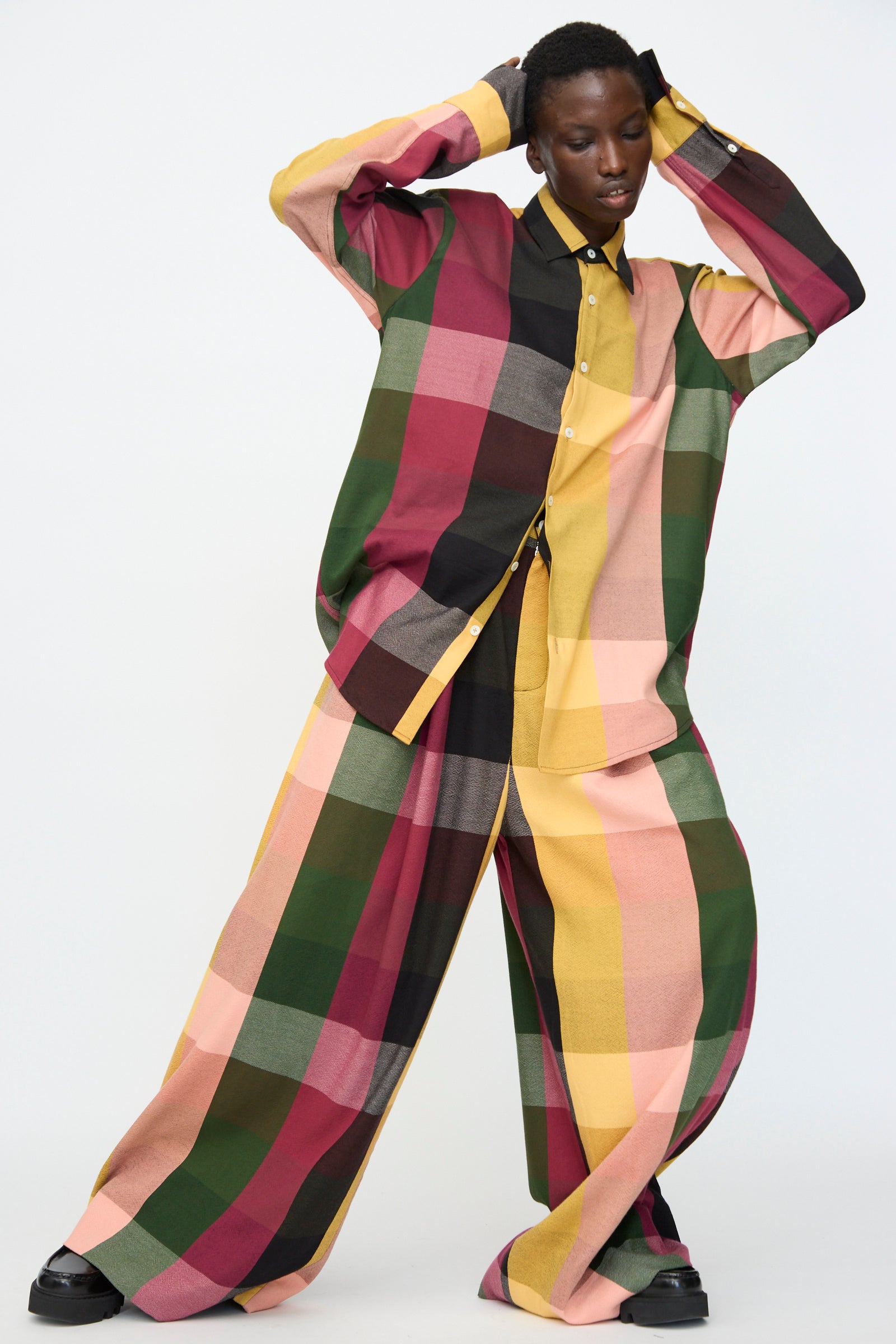 Model wearing the Marrakshi Life High Waisted Pleated Trouser in Plaid Multi, an oversized matching set with wide-leg trousers and a button-up shirt in green, burgundy, yellow, pink, and brown cotton plaid.