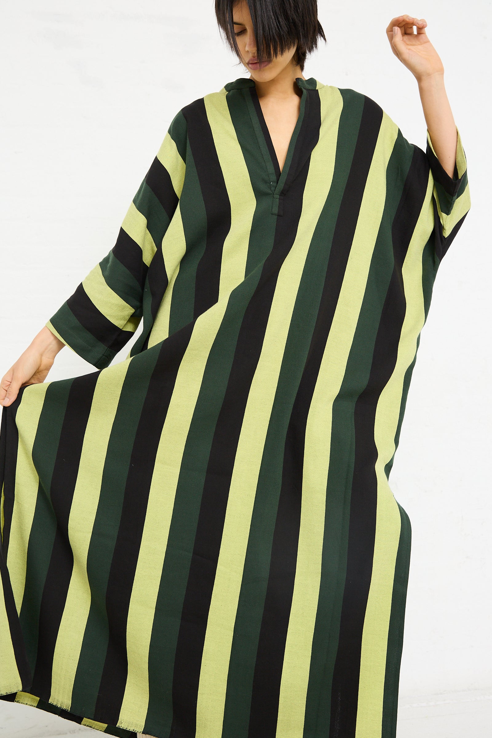 A woman in an oversized Nero Collar Caftan in Green Stripe from Marrakshi Life posing against a white background.