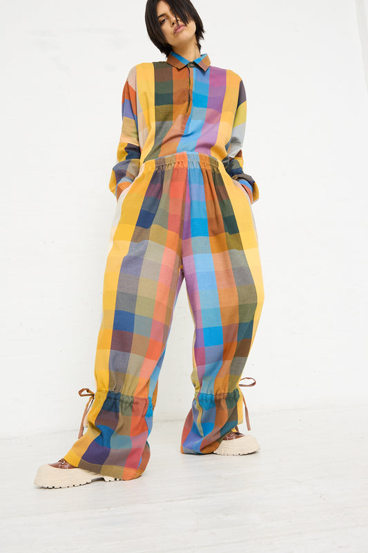 Person standing in a white room wearing a Marrakshi Life Parachute Pant in Multi Check with oversized fit and drawstring ankle cuffs.