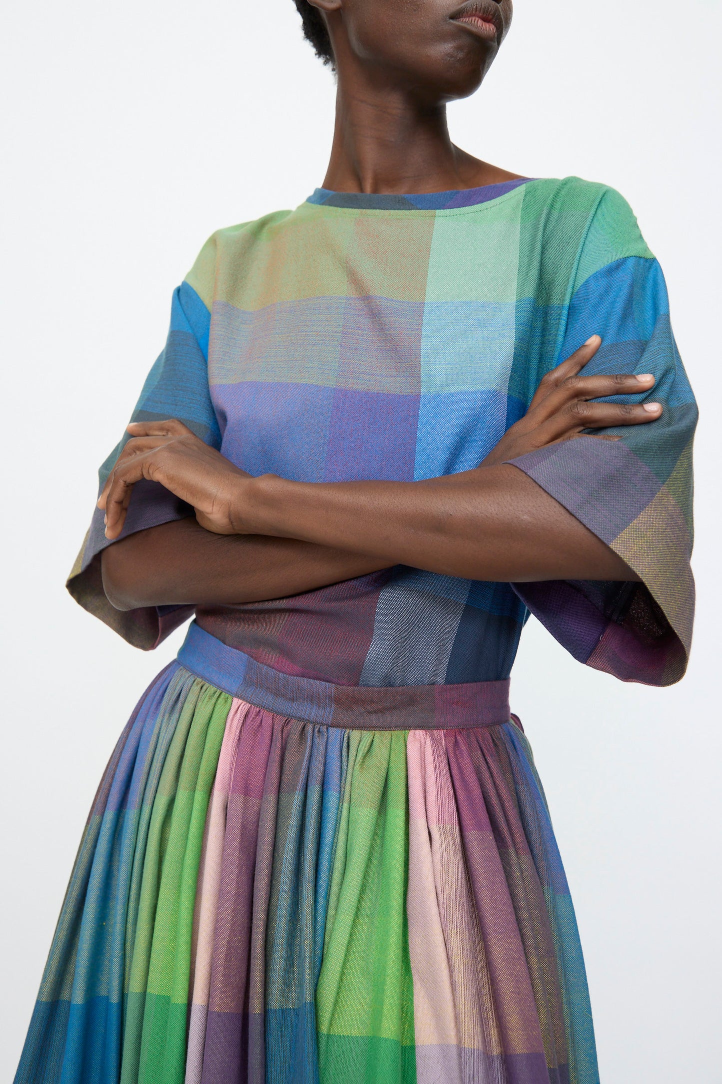 A person wearing the Marrakshi Life Puffer Skirt in Plaid Multi stands with arms crossed against a plain background—a stylish example of women's skirts.