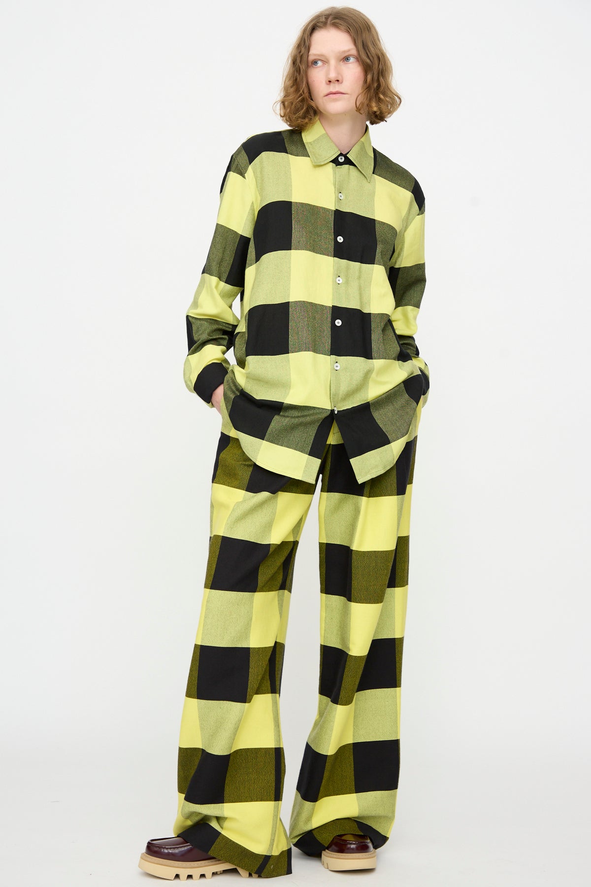 A person wearing the Marrakshi Life “The French Cuff Shirt in Plaid Black and Sunny” with matching wide-leg pants, standing against a plain white background.