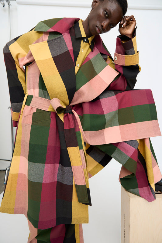 A person models the Marrakshi Life Trench Coat in Plaid Multi with matching pants—an oversized, colorful set in pink, yellow, green, and burgundy—posed against a plain studio background.