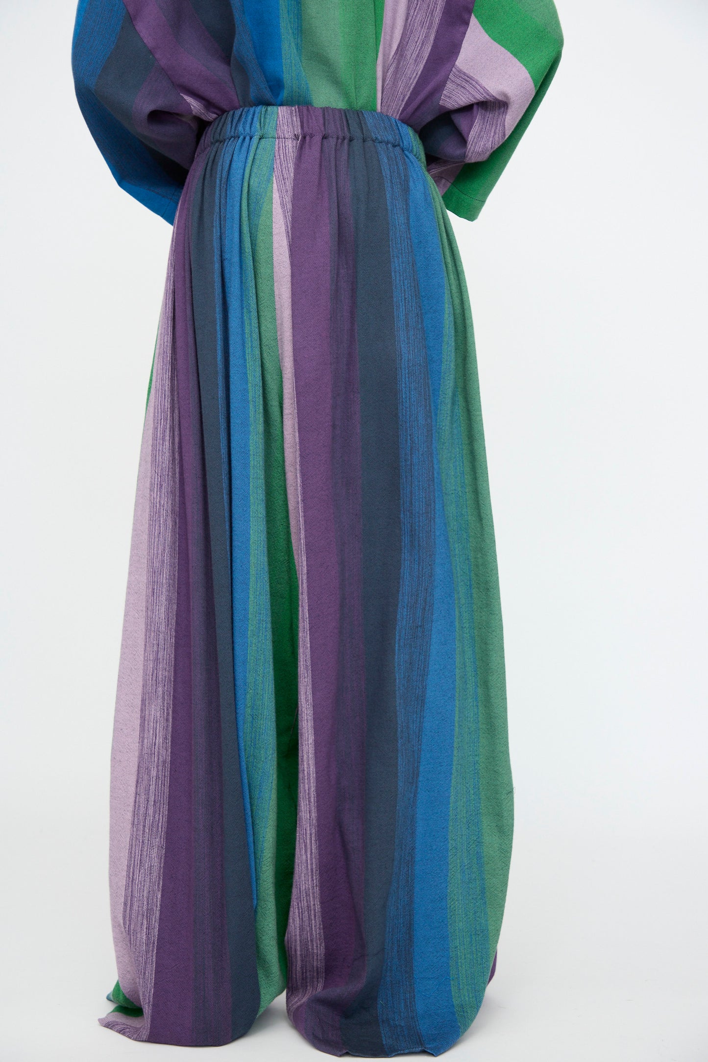 Model wears the Marrakshi Life Wide Leg Pant in Stripe Multi—loose, oversized cotton pants with an elasticated waist, featuring purple, blue, green, and teal stripes—shown against a plain white background.