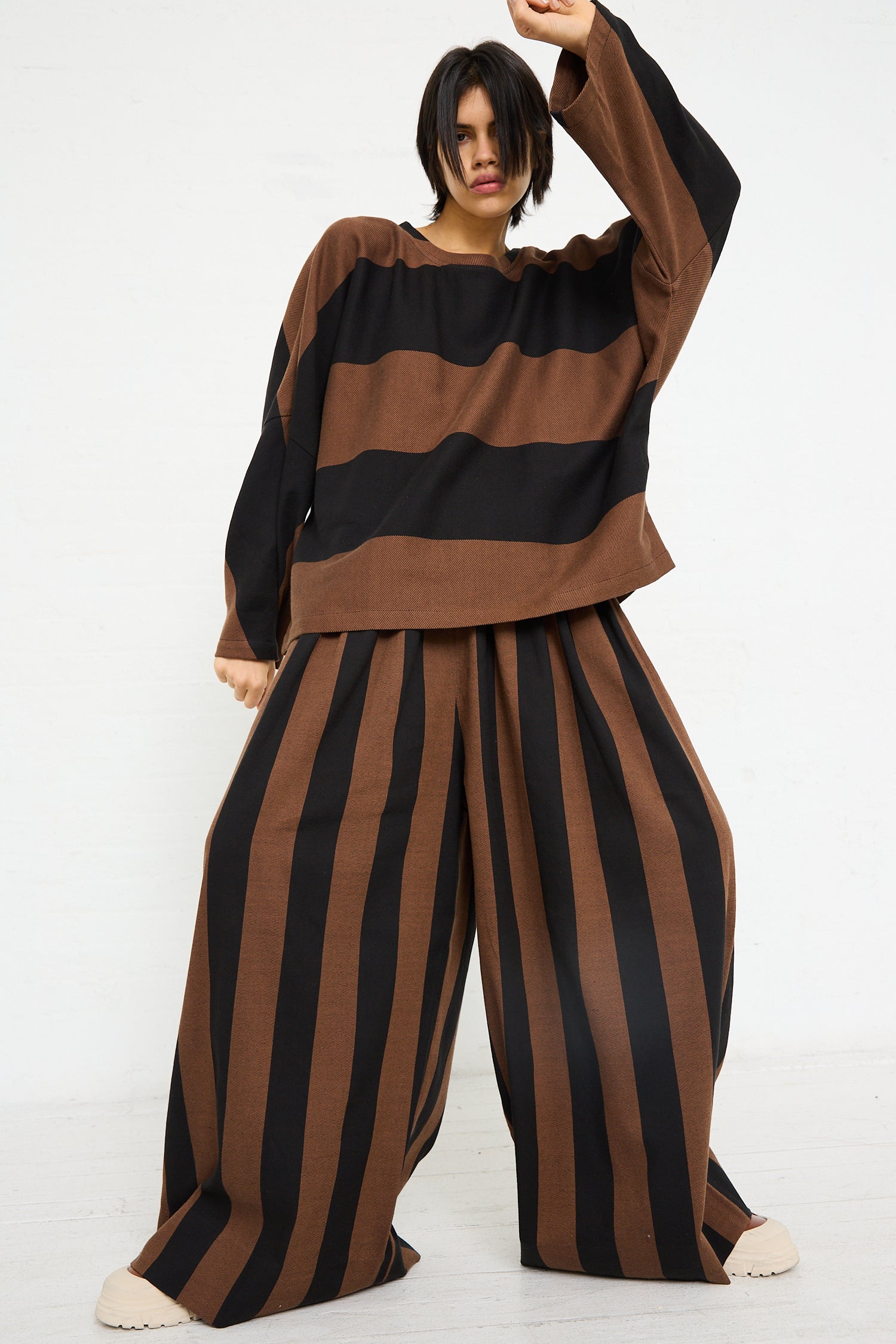 A model wearing the Drawstring Pleated Pant in Black and Brown Stripe by Marrakshi Life - OROBORO NYC