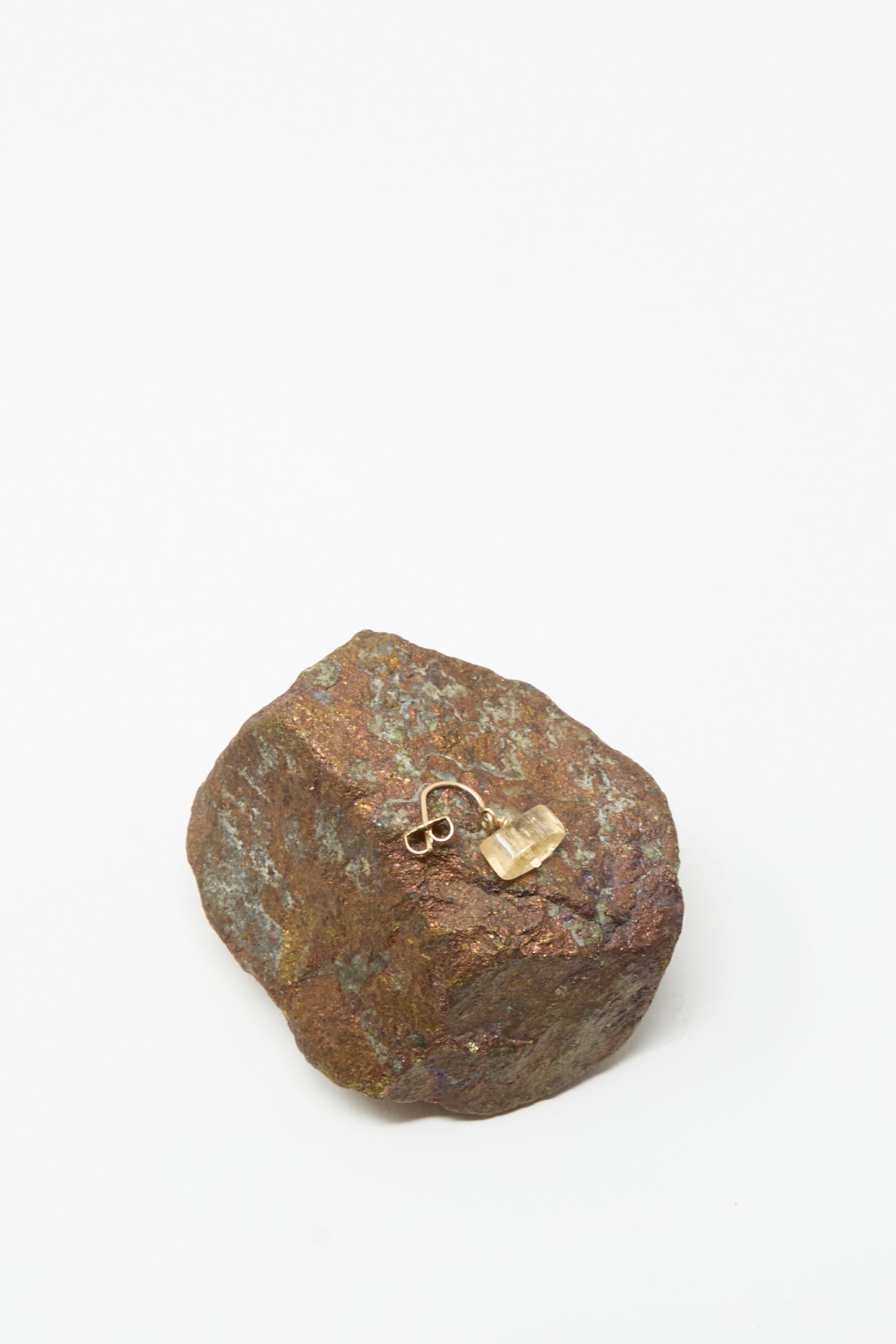 The Mary MacGill 14K Crescent Charm Earring in Imperial Topaz is displayed on a rough, brown rock against a plain white background.