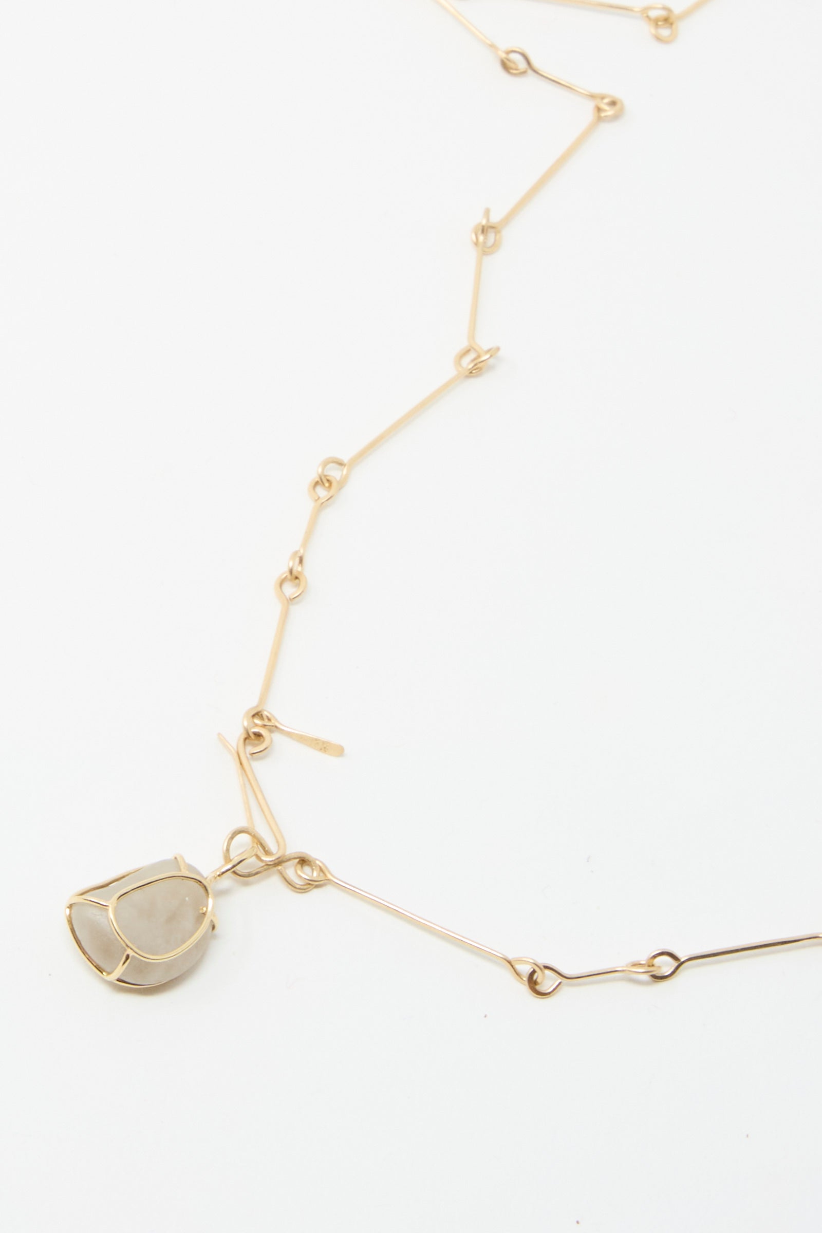 The exquisite 14K Floating Bone Chain Necklace by Mary MacGill features a handmade design, highlighting a geometric pendant adorned with a Block Island stone encased in a wireframe setting.