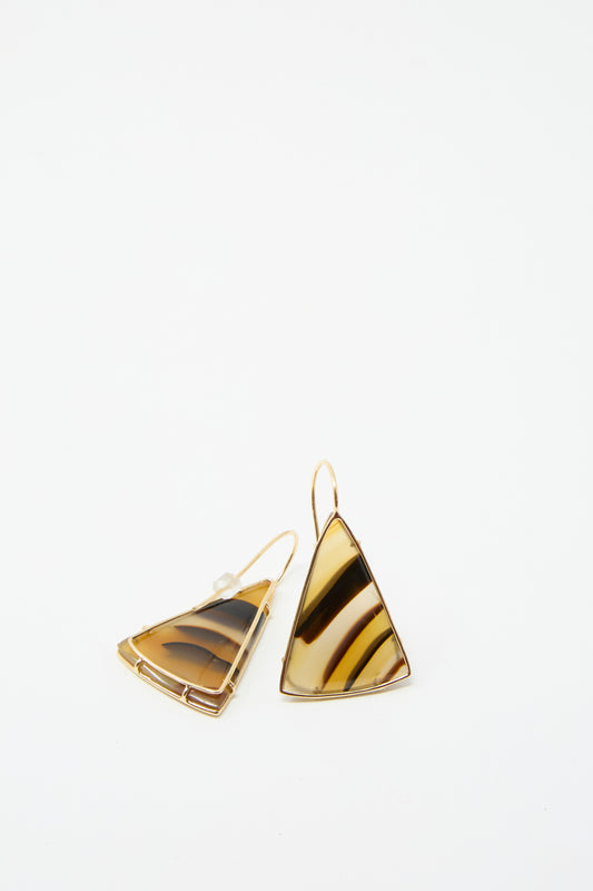 Two 14K gold-trimmed earrings, showcasing a striking banded agate design in triangular drop style, set against a plain white background by Mary MacGill.