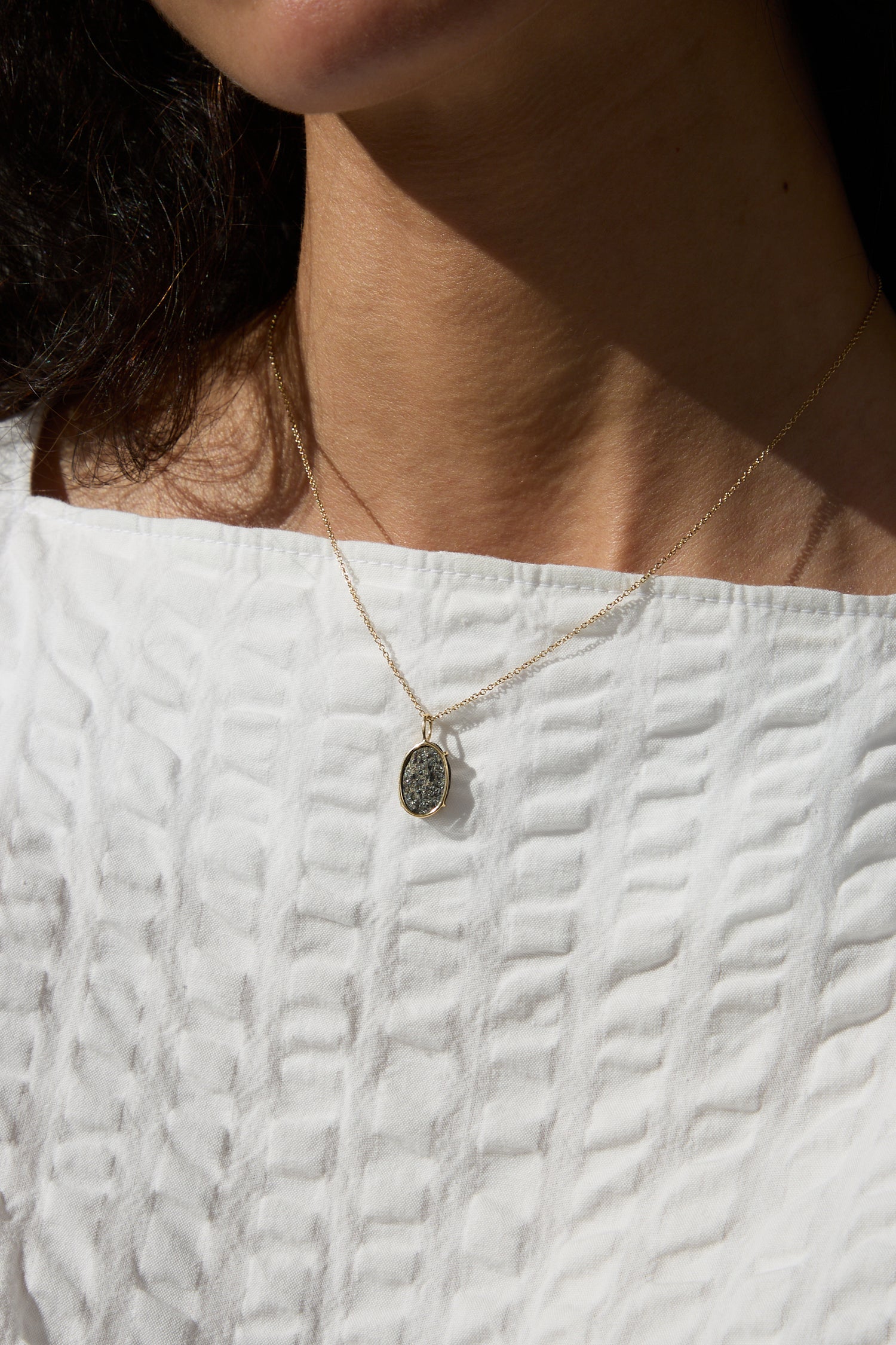 A person wearing a Mary MacGill 14K Floating Necklace in Block Island Stone accentuated by 14k gold.