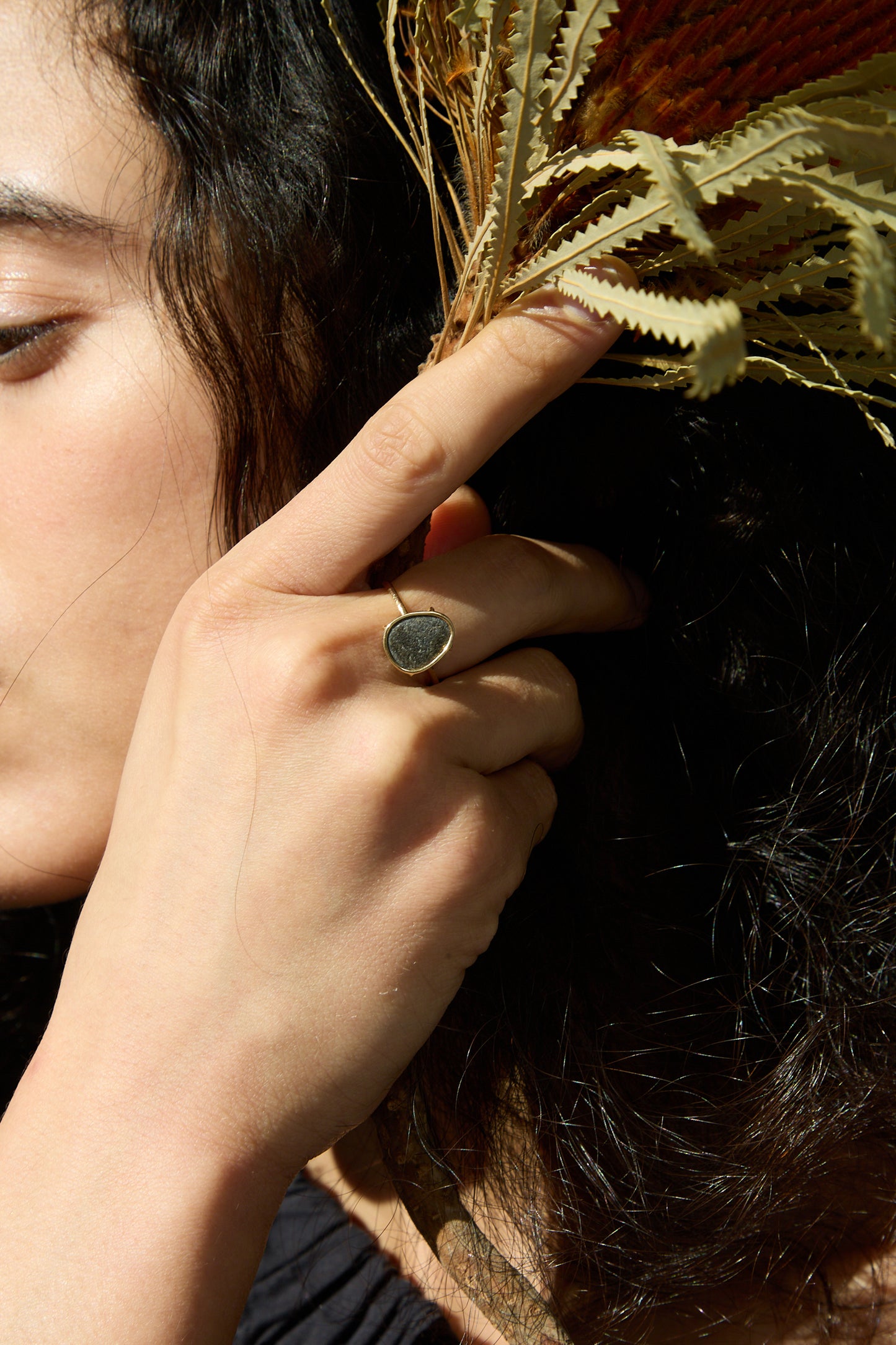 A close up of a woman's hand holding a Mary MacGill 14K Floating Ring in Island Stone.