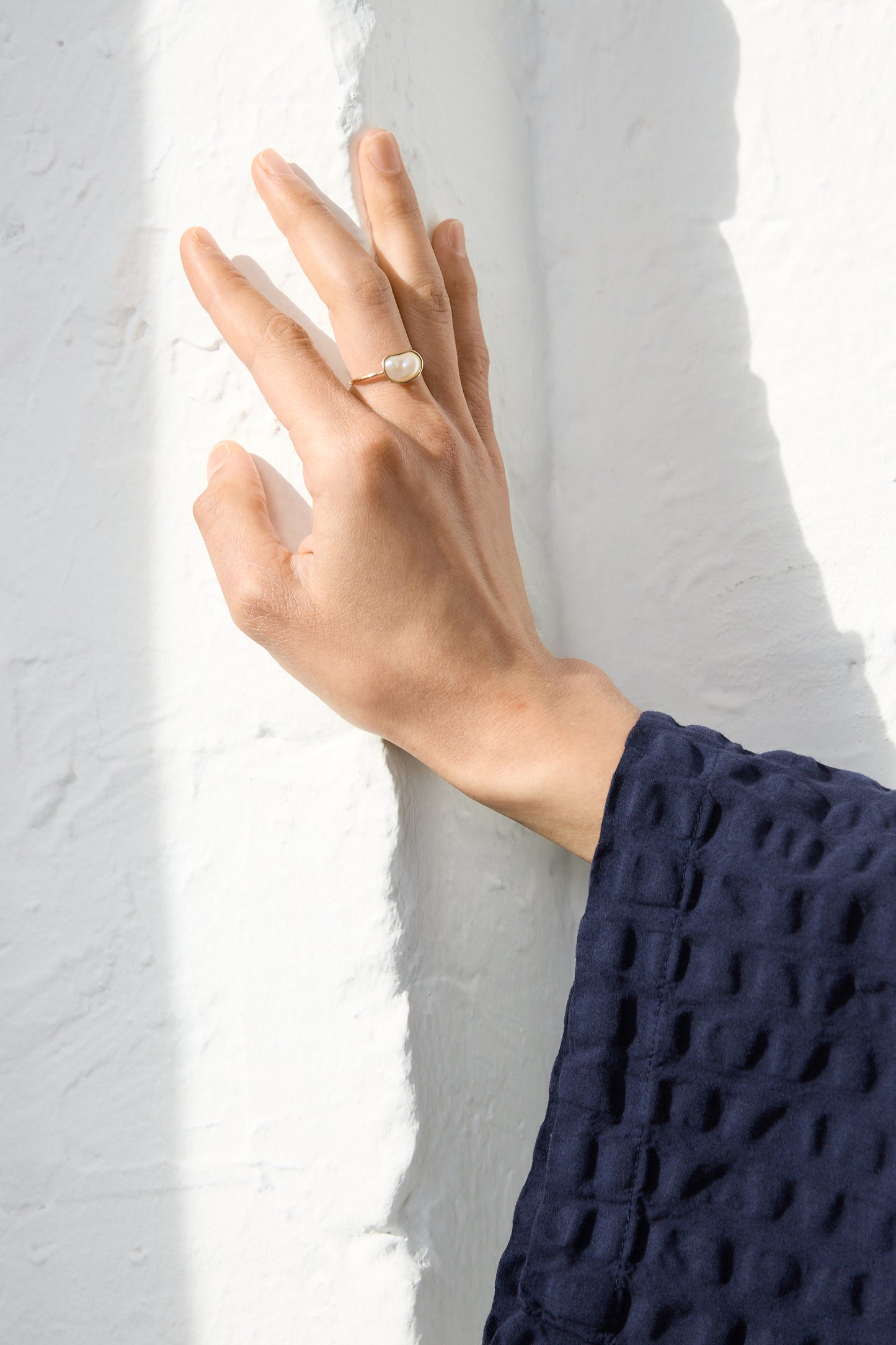 A Mary MacGill 14K Floating Ring in Pearl adorns the hand, beautifully showcasing a handmade pearl accessory.