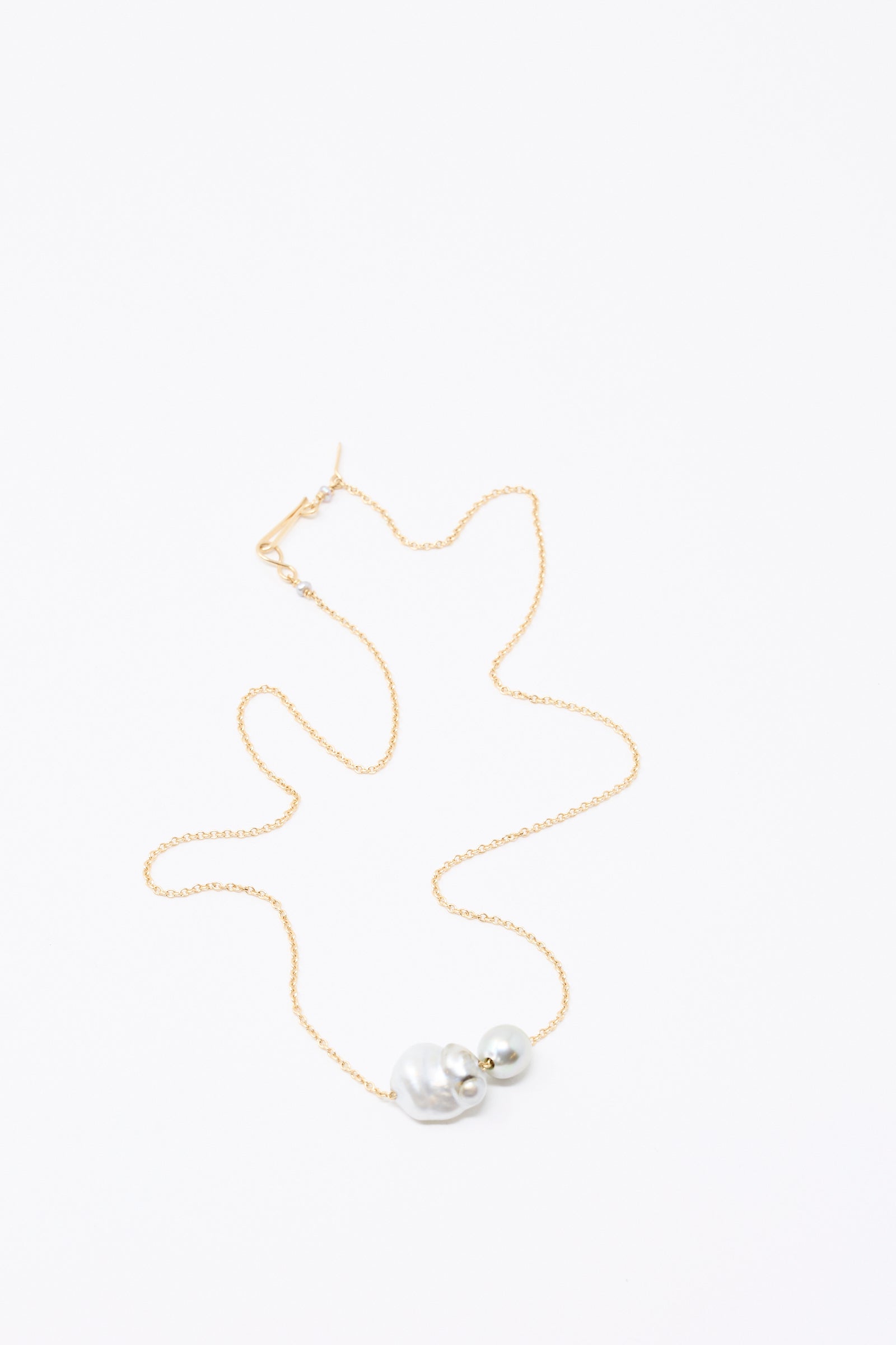The 14K Mermaids Purse Necklace by Mary MacGill features Keshi and Tahitian pearls on a delicate gold chain, displayed elegantly on a white surface.