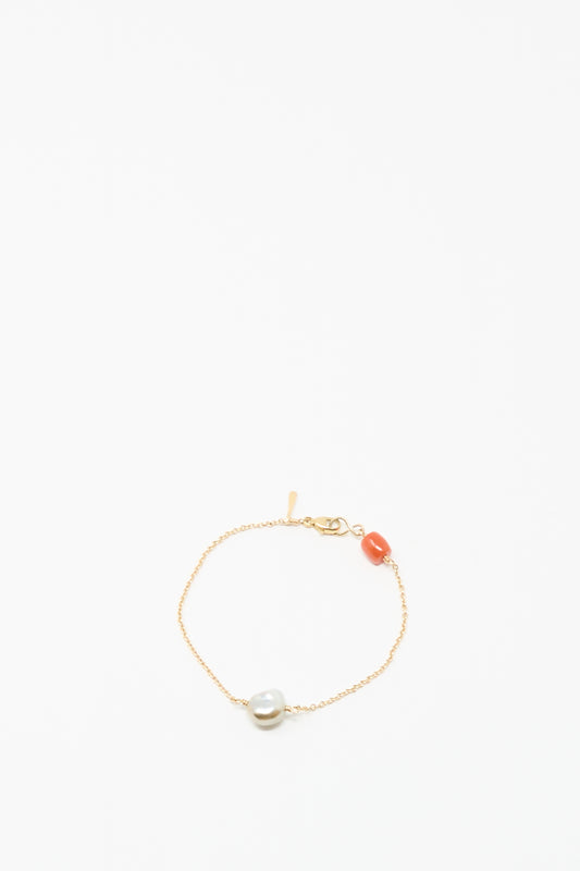 The Mary MacGill 14K Stone Chain Bracelet in Coral and Keshi pearl features a single white Keshi pearl and orange coral bead on a delicate gold chain, shown against a plain white background.