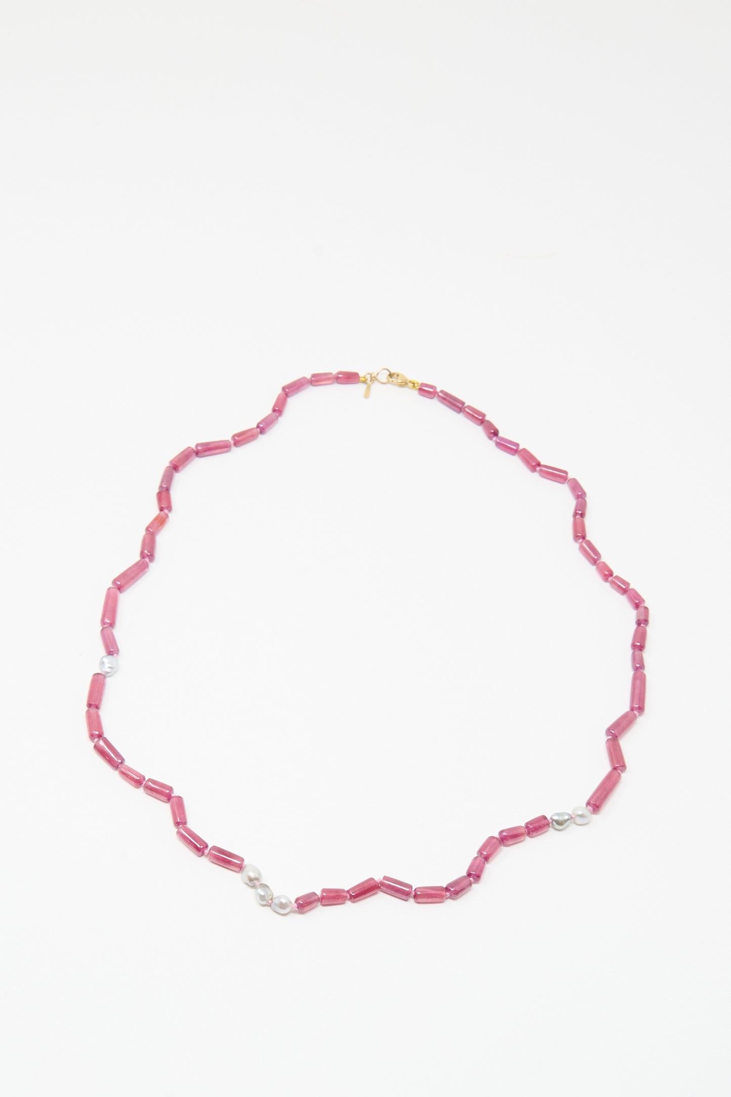 The Mary MacGill 14K Stone Layering Necklace features cylindrical ruby beads, small Keshi pearls, and a gold clasp, arranged in an elegant oval on a white background.