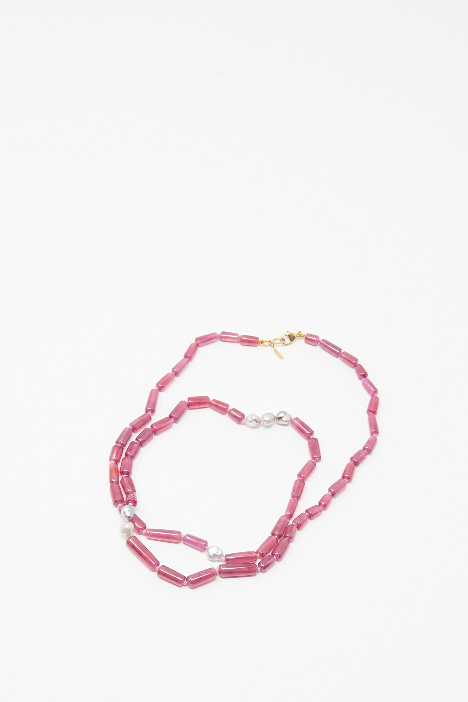 The Mary MacGill 14K Stone Layering Necklace features ruby and Keshi pearl stones with a gold clasp, arranged in a loose spiral on a white background.