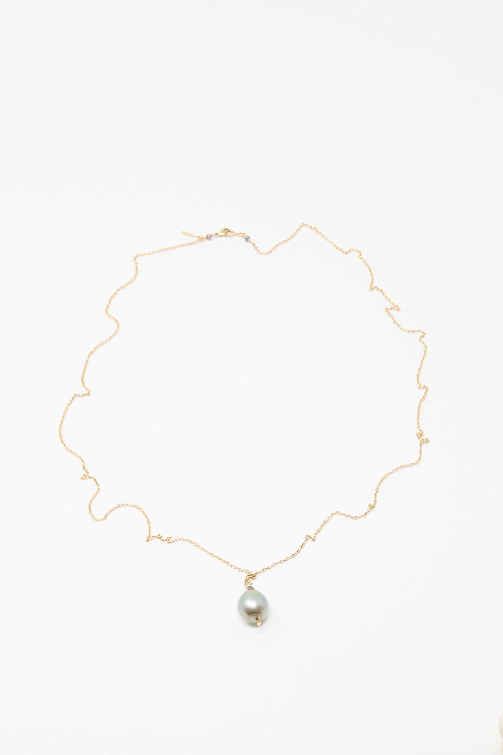 The Mary MacGill 14K Tahitian Pearl Drop Necklace in Charcoal Silver features a single round pearl on a delicate gold chain, handmade and displayed on a white background.