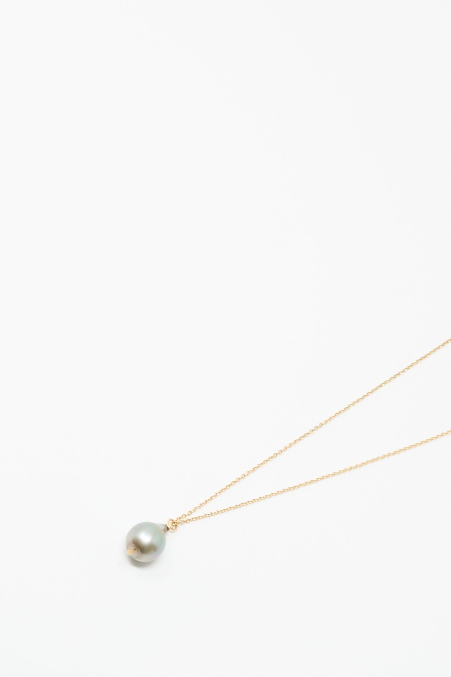 The Mary MacGill 14K Tahitian Pearl Drop Necklace in Charcoal Silver showcases a delicate handmade gold chain with a single round Tahitian pearl pendant, displayed on a plain white background.