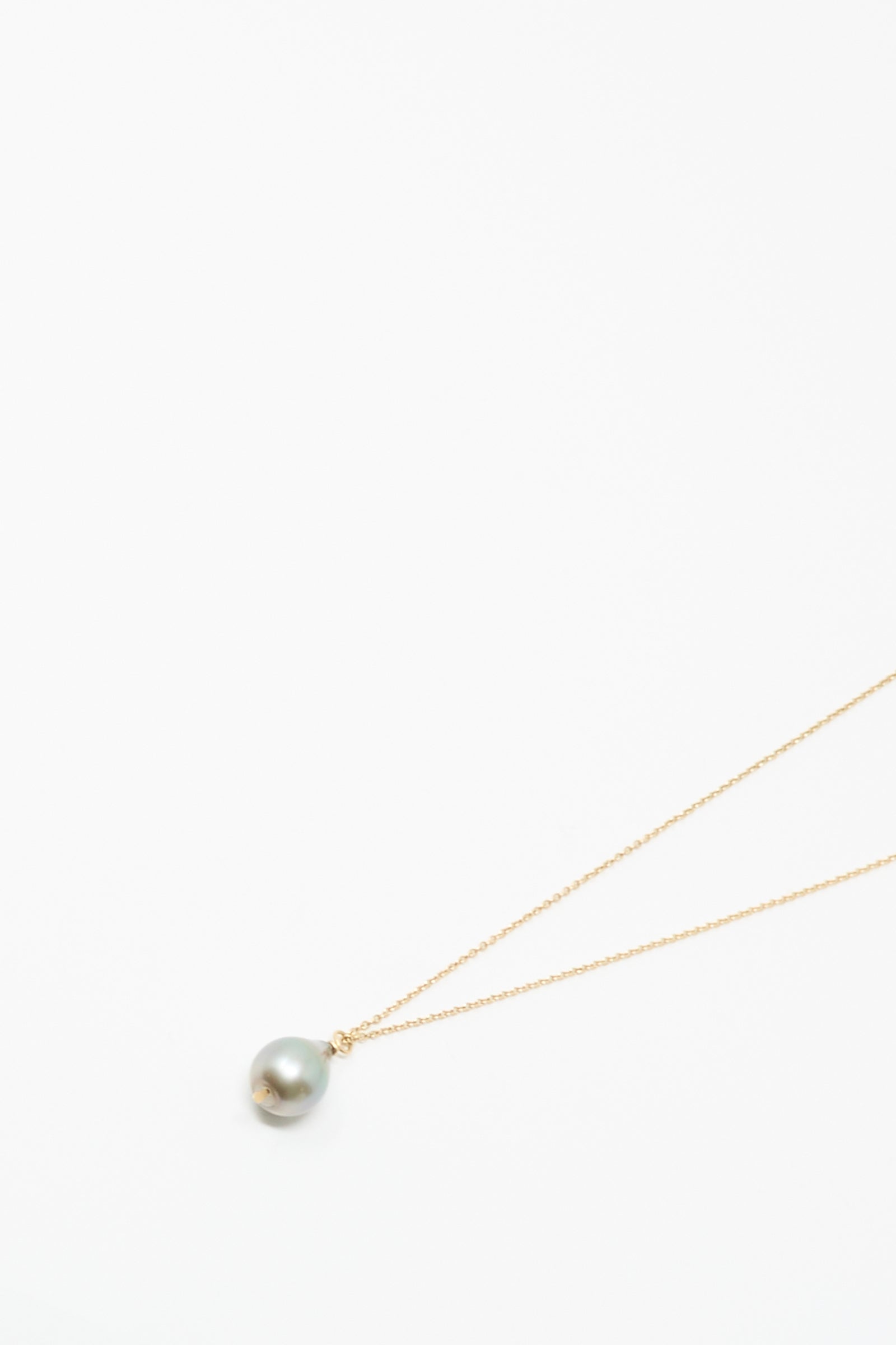 The Mary MacGill 14K Tahitian Pearl Drop Necklace in Charcoal Silver showcases a delicate handmade gold chain with a single round Tahitian pearl pendant, displayed on a plain white background.