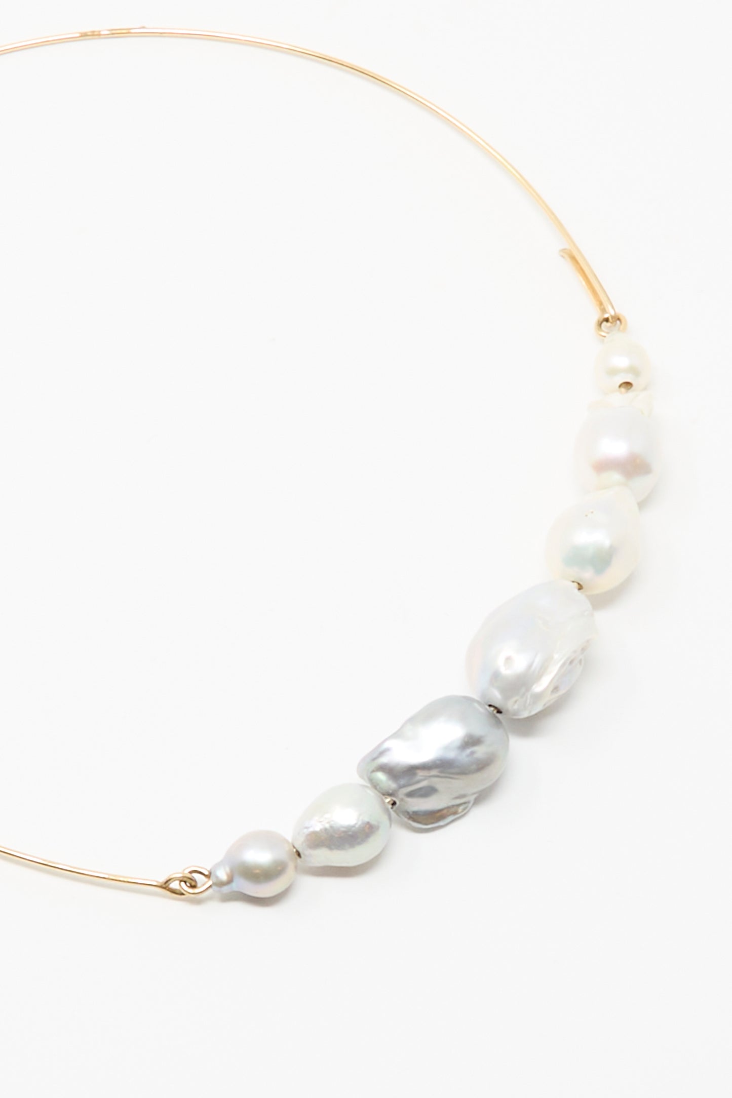 The Mary MacGill Baroque Pearl Crescent Collar in Silver and White is a gold choker necklace adorned with handmade, irregularly shaped Baroque pearls.