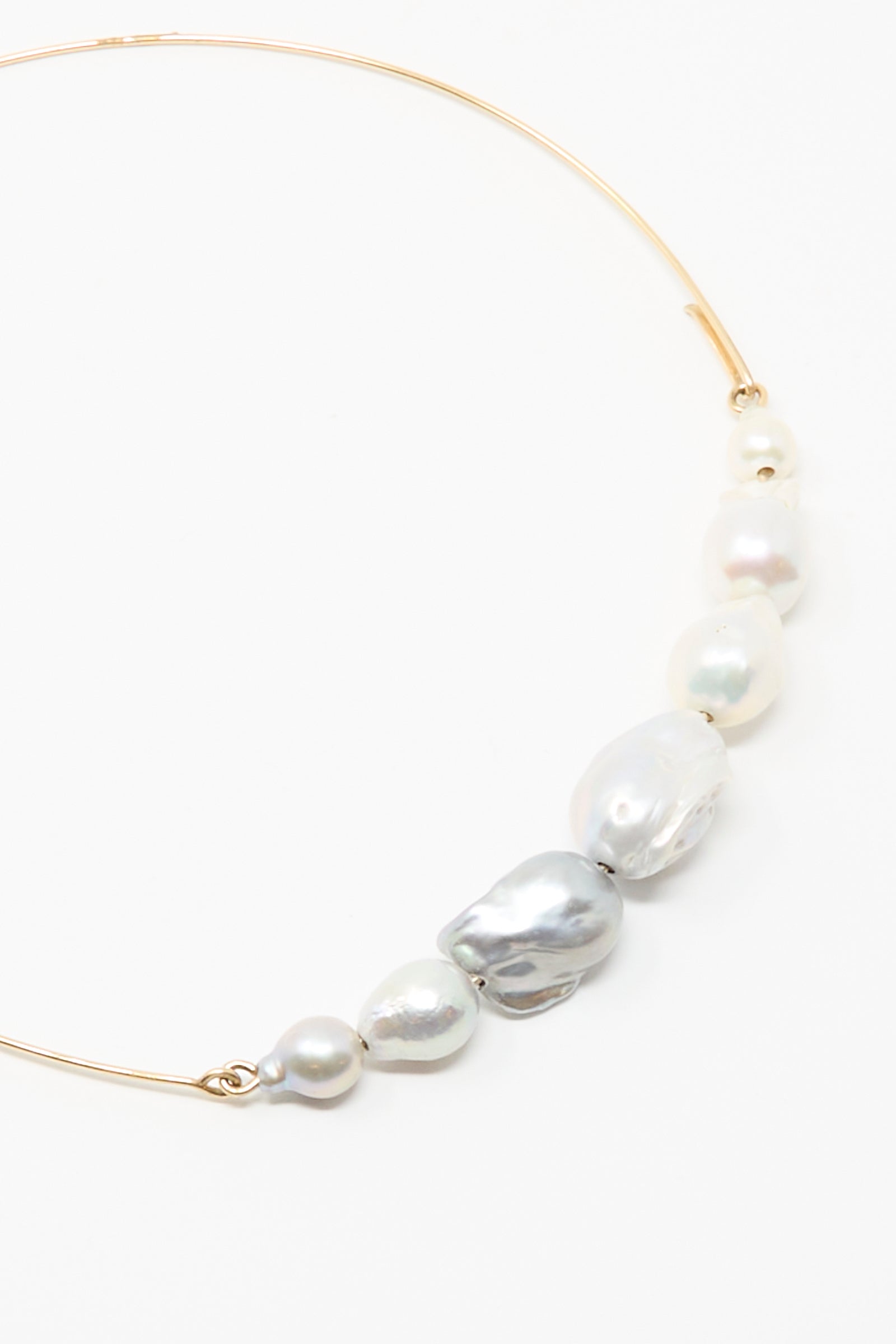 The Mary MacGill Baroque Pearl Crescent Collar in Silver and White is a gold choker necklace adorned with handmade, irregularly shaped Baroque pearls.