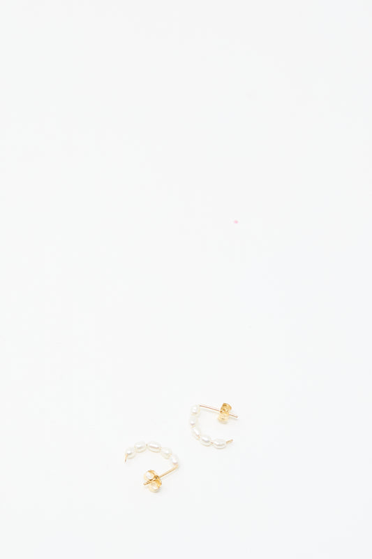 Mary MacGill's Baroque Pearl Crescent Hoops are handmade earrings featuring gold studs and small pearls in a curved design, inspired by Baroque styles and shown on a plain white background.