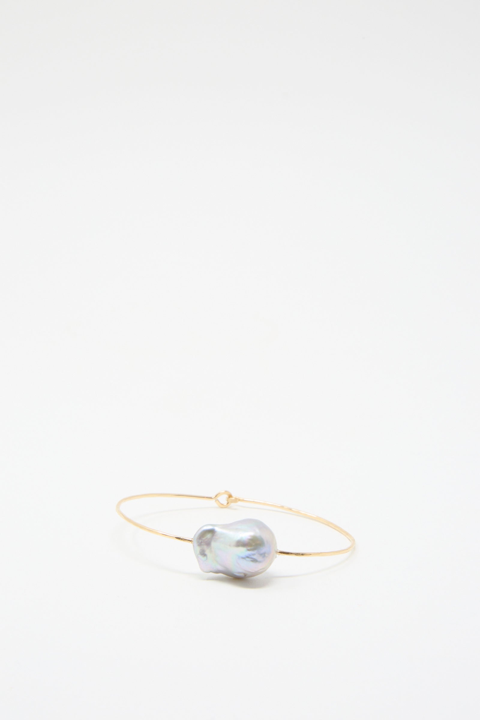 The Baroque Pearl Cuff Bracelet in Silver by Mary MacGill features a striking large, irregular Baroque pearl at its center, elegantly contrasted against shimmering hammered silver wire, all set on a plain white background.