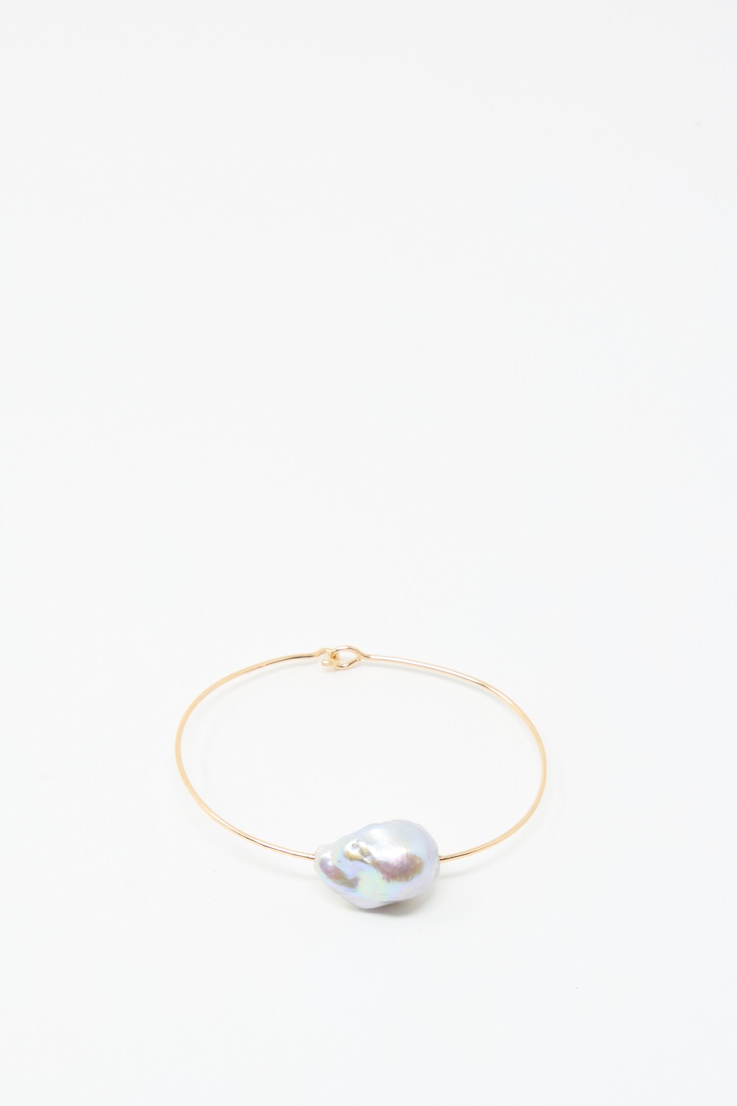 The Baroque Pearl Cuff Bracelet in Silver by Mary MacGill features a single, uniquely shaped baroque pearl on a sleek silver cuff, displayed against a plain white background.