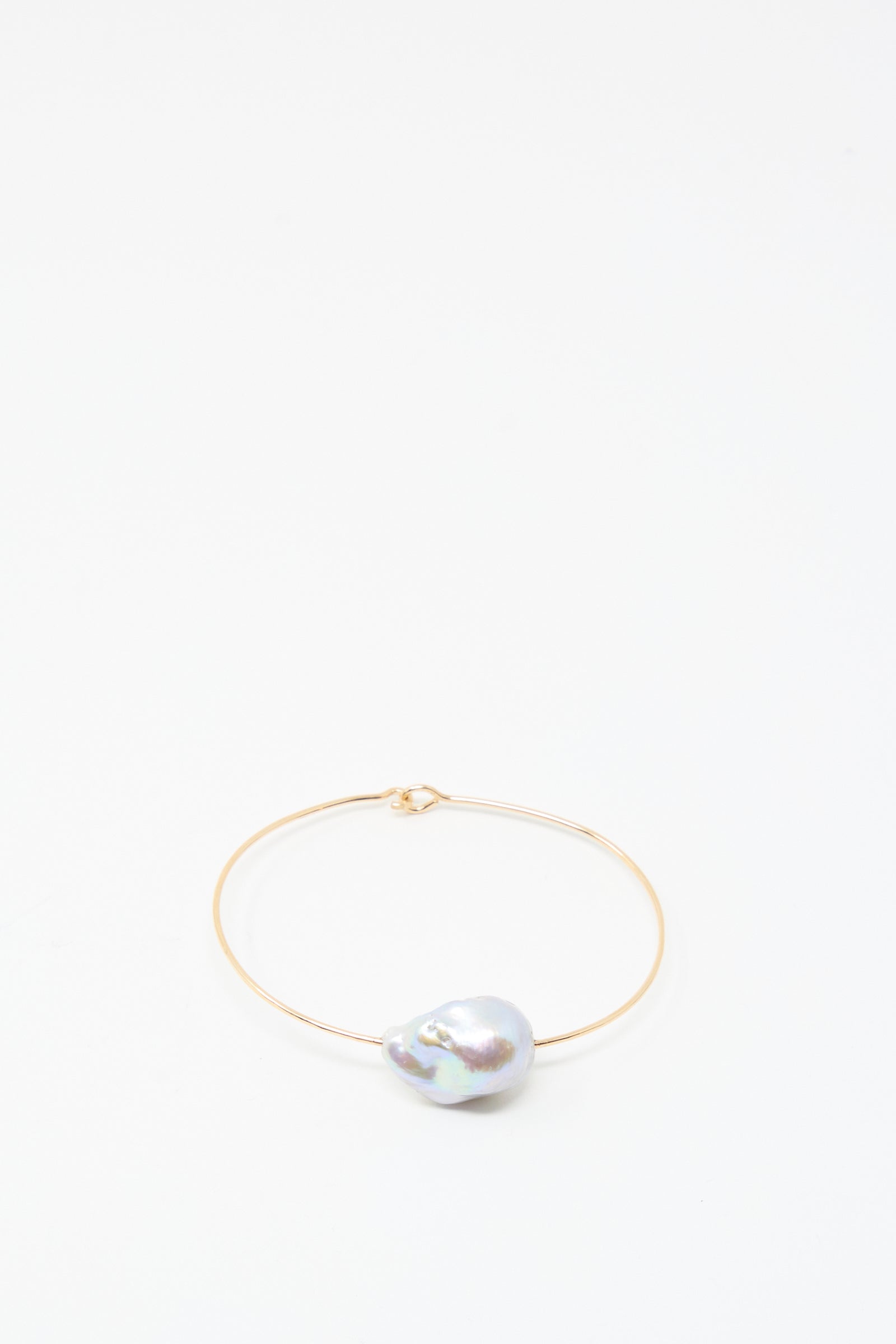 The Baroque Pearl Cuff Bracelet in Silver by Mary MacGill features a single, uniquely shaped baroque pearl on a sleek silver cuff, displayed against a plain white background.