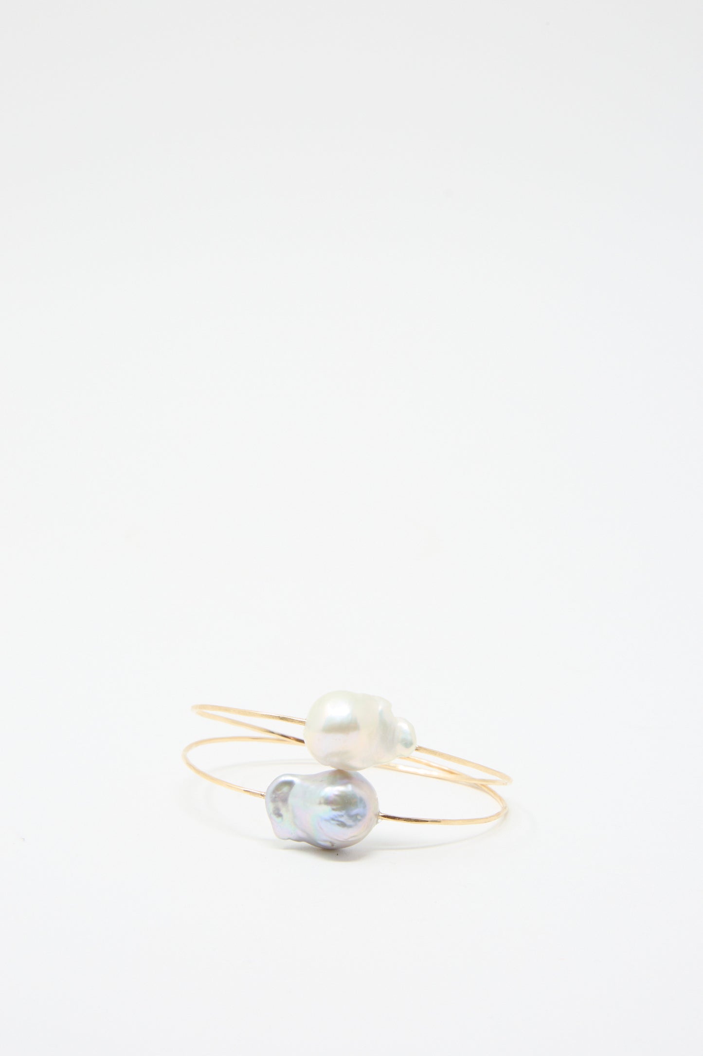 Two Baroque Pearl Cuff Bracelets in Silver by Mary MacGill, each expertly crafted from hammered wire and featuring a single Baroque pearl, are displayed on a plain white background.