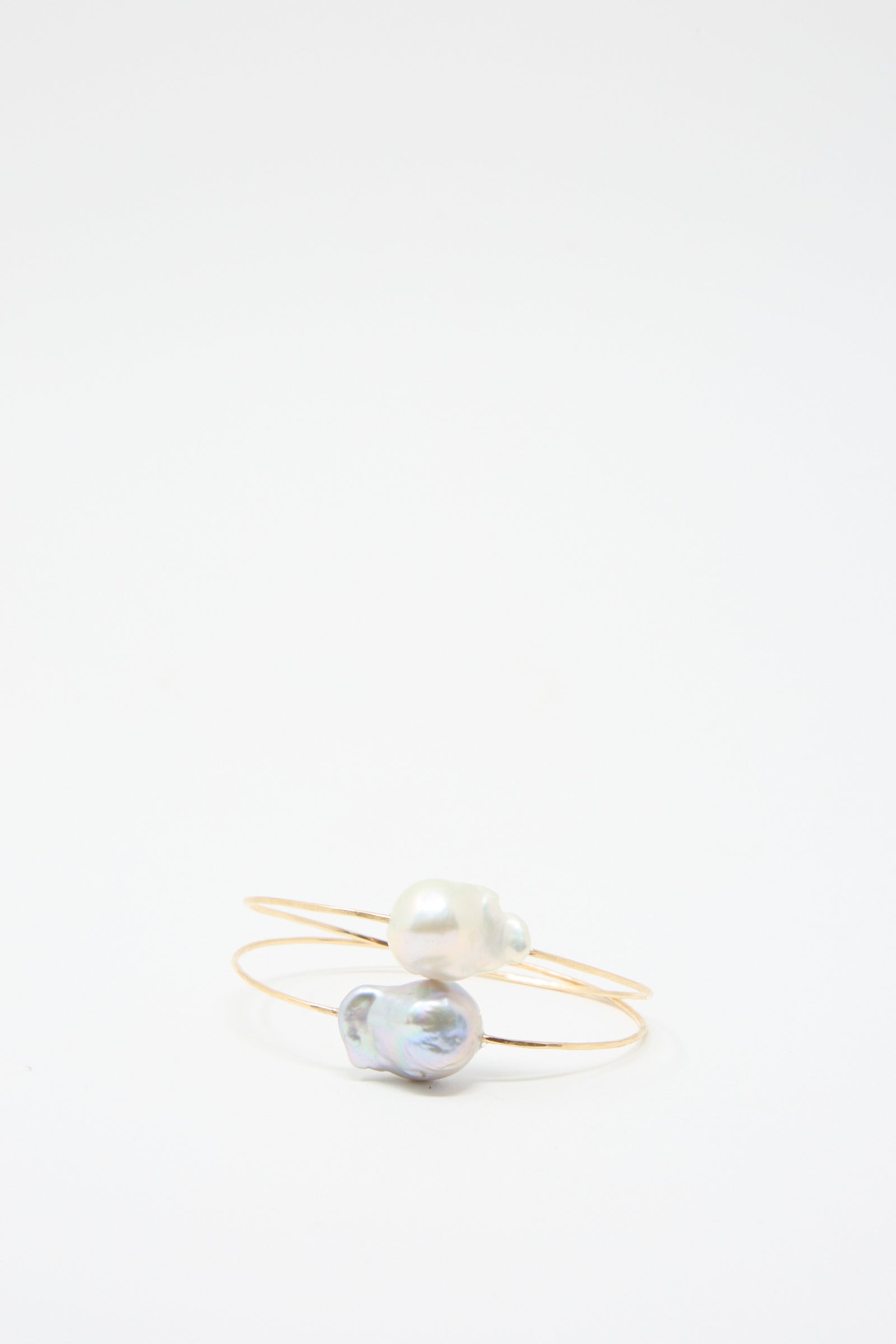 Two Baroque Pearl Cuff Bracelets in Silver by Mary MacGill, each expertly crafted from hammered wire and featuring a single Baroque pearl, are displayed on a plain white background.