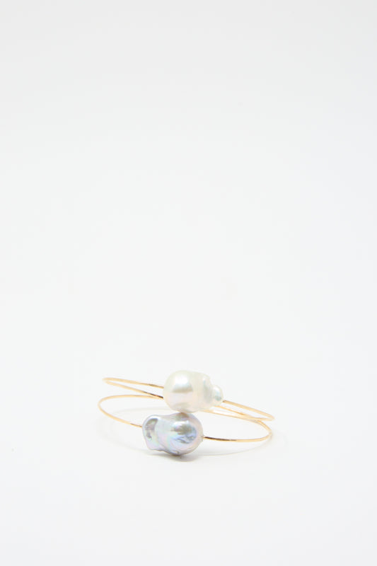 Two Baroque Pearl Cuff Bracelets in Silver by Mary MacGill, each expertly crafted from hammered wire and featuring a single Baroque pearl, are displayed on a plain white background.