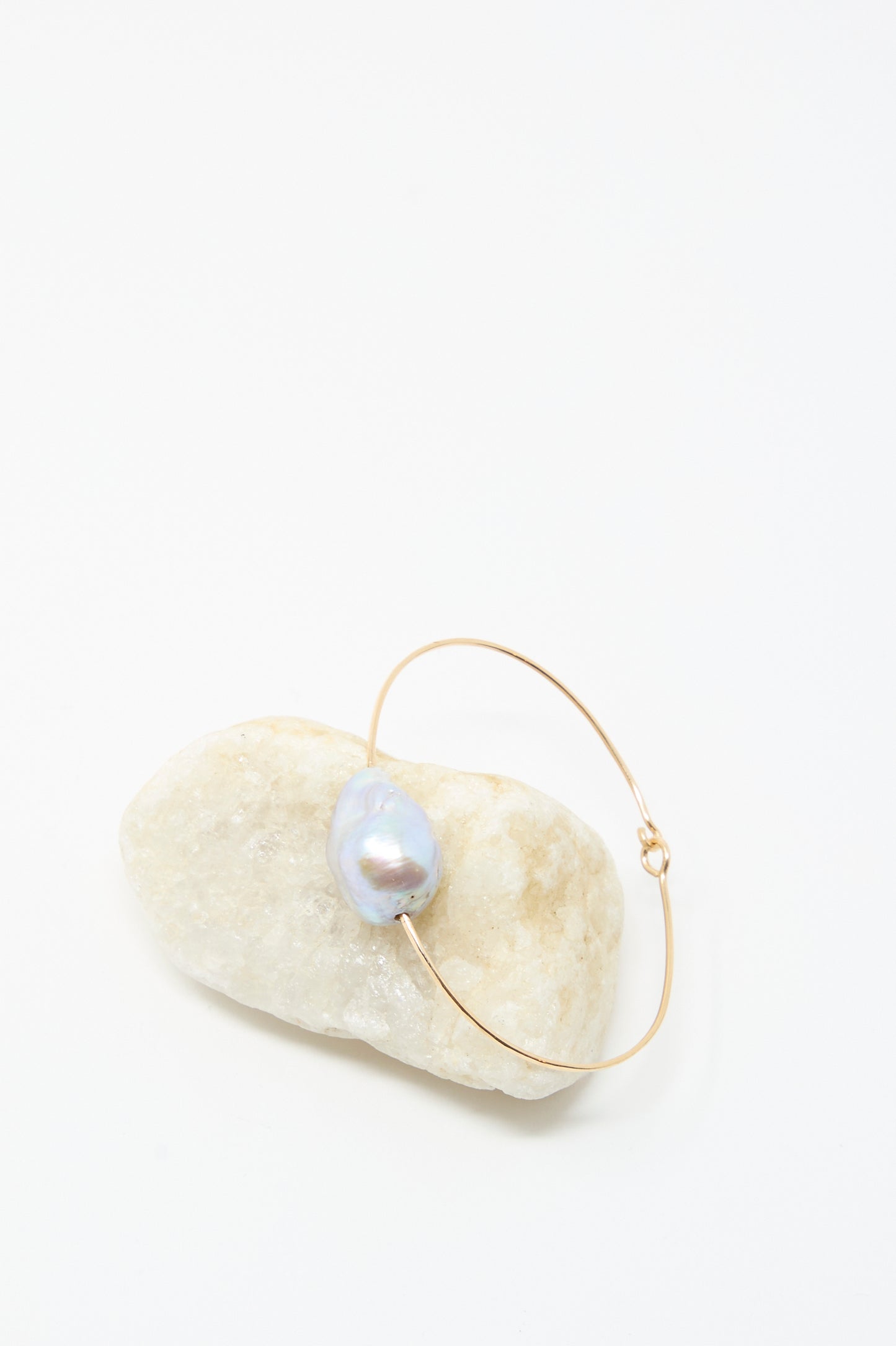 The Mary MacGill Baroque Pearl Cuff Bracelet in Silver is displayed with a single baroque pearl on a smooth white stone against a plain white background.