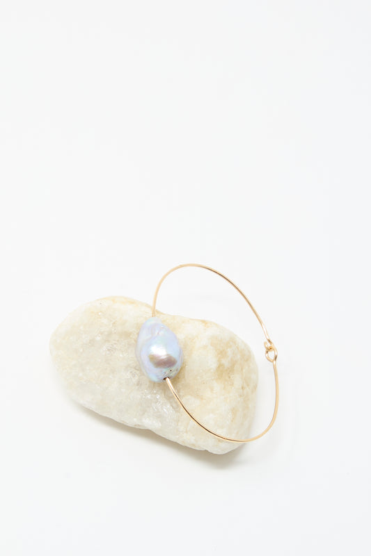 The Mary MacGill Baroque Pearl Cuff Bracelet in Silver is displayed with a single baroque pearl on a smooth white stone against a plain white background.
