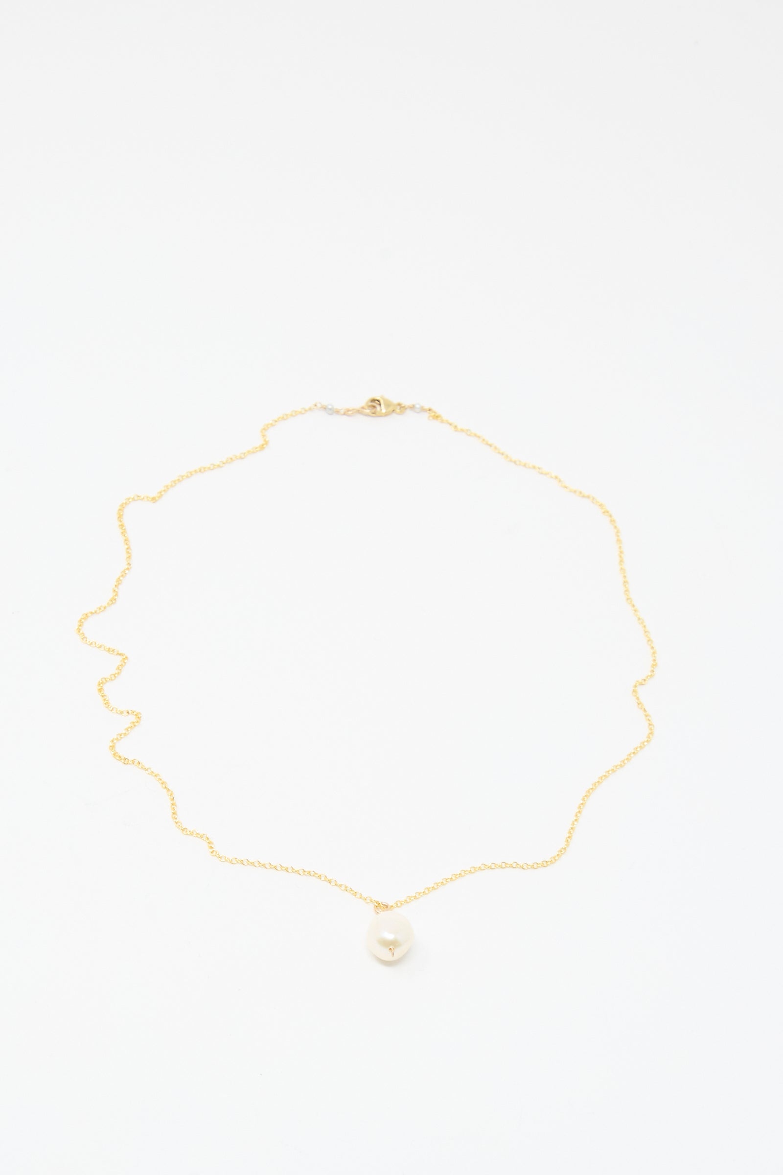 The Mary MacGill Baroque Pearl Drop Necklace in White - 18" is a handmade gold chain with a single round baroque pearl pendant, shown on a white background.