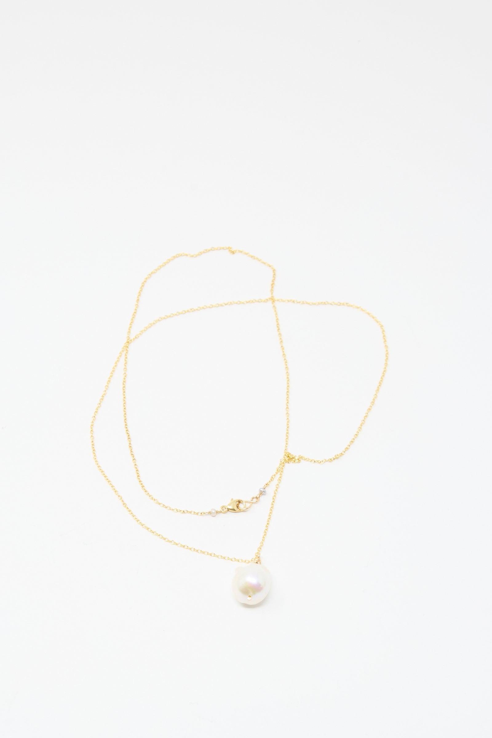 The Mary MacGill Baroque Pearl Drop Necklace in White (28") is a delicate handmade gold chain with a single round white pearl pendant, echoing classic baroque style, shown on a plain white background.