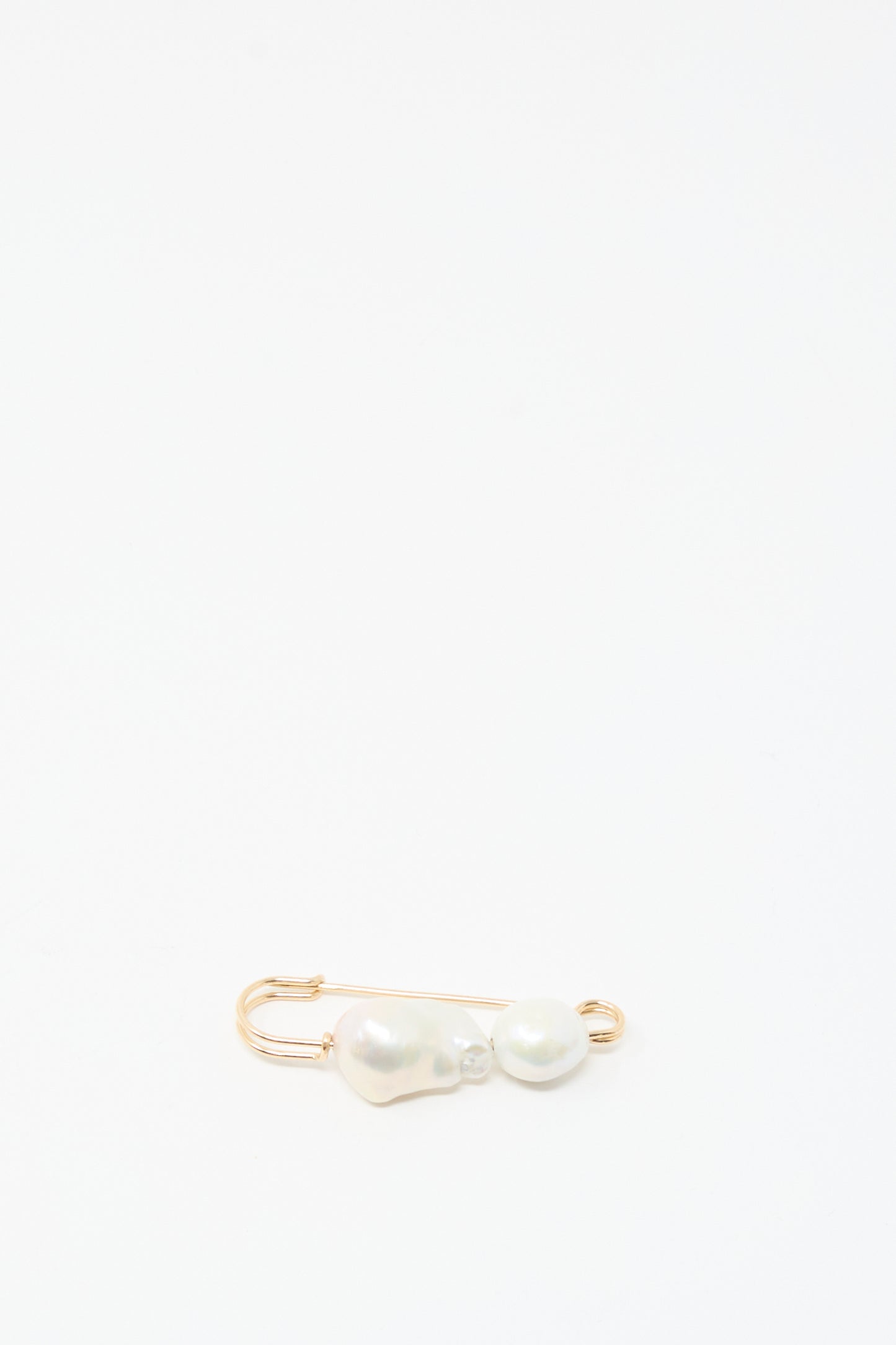 The Mary MacGill Baroque Pearl Pin in White, crafted with gold-filled wire and two Baroque pearls, appears near the bottom left corner on a plain white background.