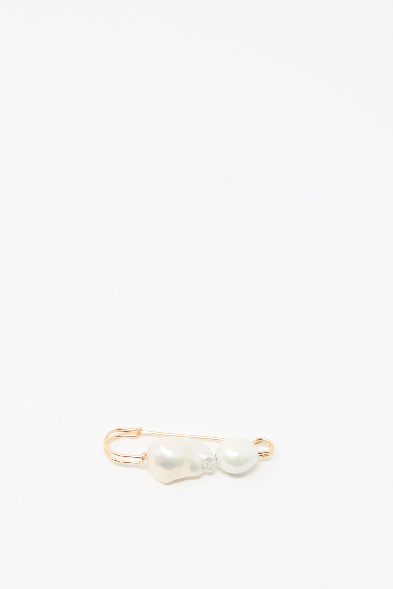 The Mary MacGill Baroque Pearl Pin in White, crafted with gold-filled wire and two Baroque pearls, appears near the bottom left corner on a plain white background.