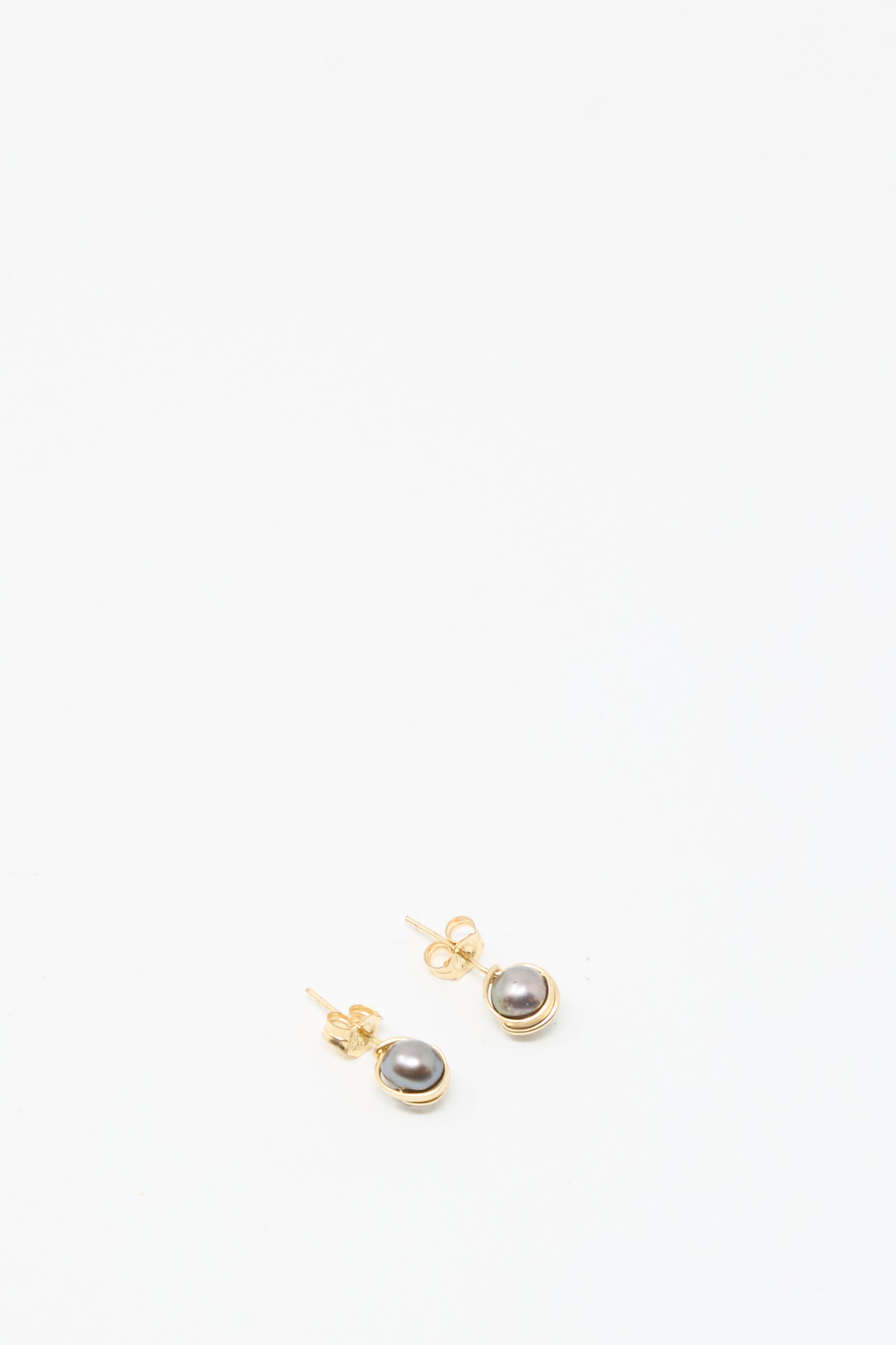The Baroque Pearl Studs in Charcoal by Mary MacGill are small gold-filled earrings with dark round pearls, shown on a plain white background.
